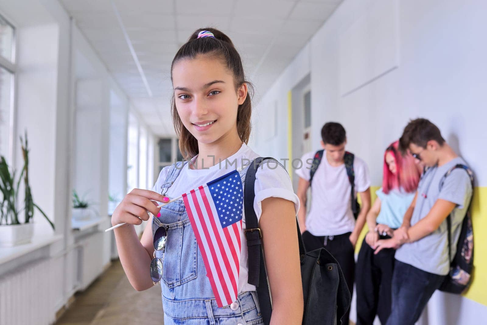 Student teenager girl with USA flag inside school, school children group background. United States of America, education and youth, patriotism people concept