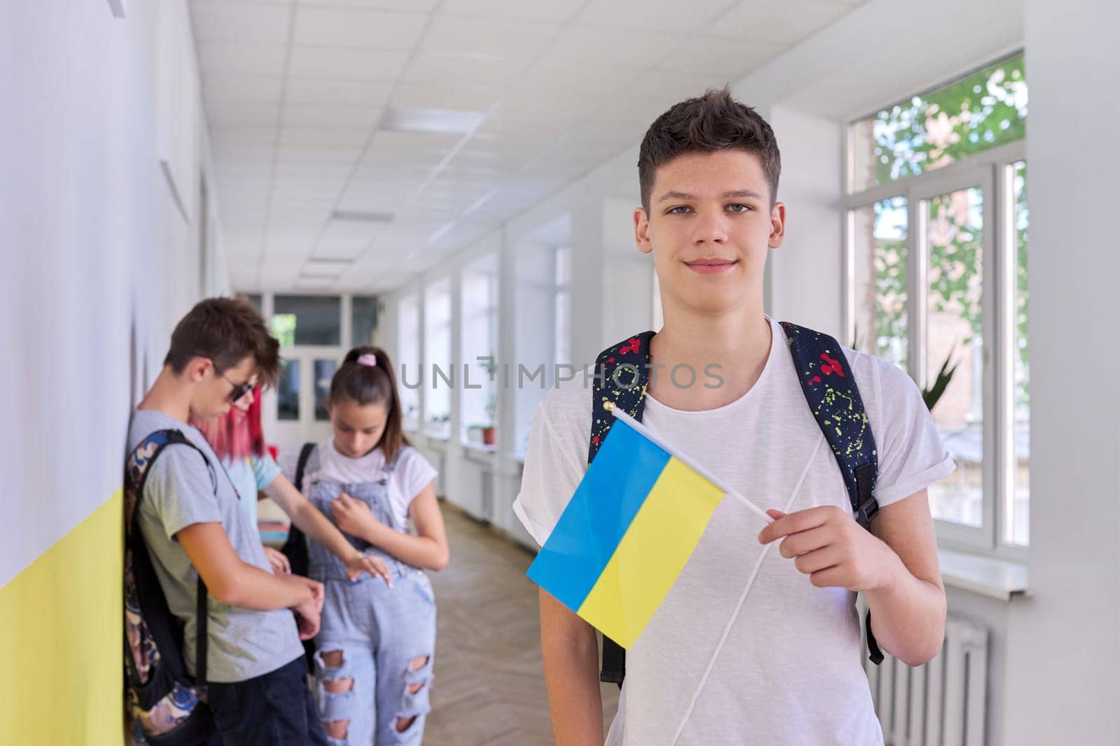 Teenager student with Ukraine flag, school corridor group of students background by VH-studio