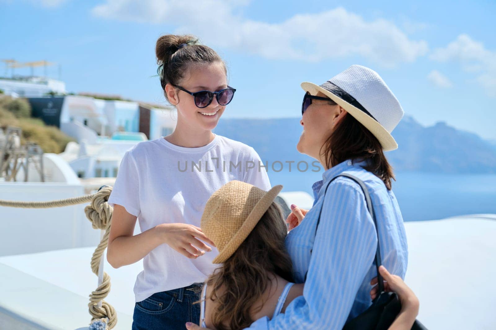 Tourism, travel, Greece, Santorini. Happy travelers mom and daughters laughing and talking on famous tourist island