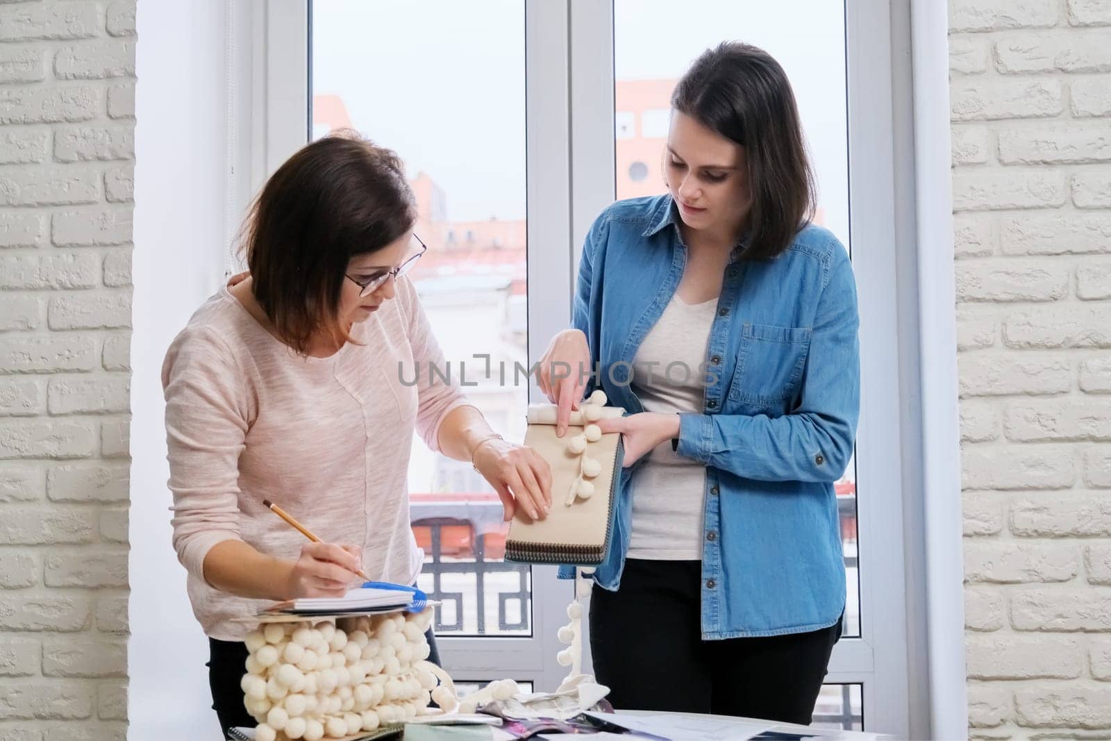 Interior design, working women designers choosing samples of fabrics and accessories for curtains