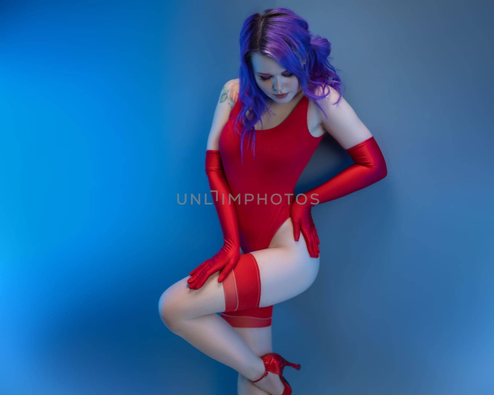 the sexy girl in red bodysuit stockings and red gloves poses erotically against the background