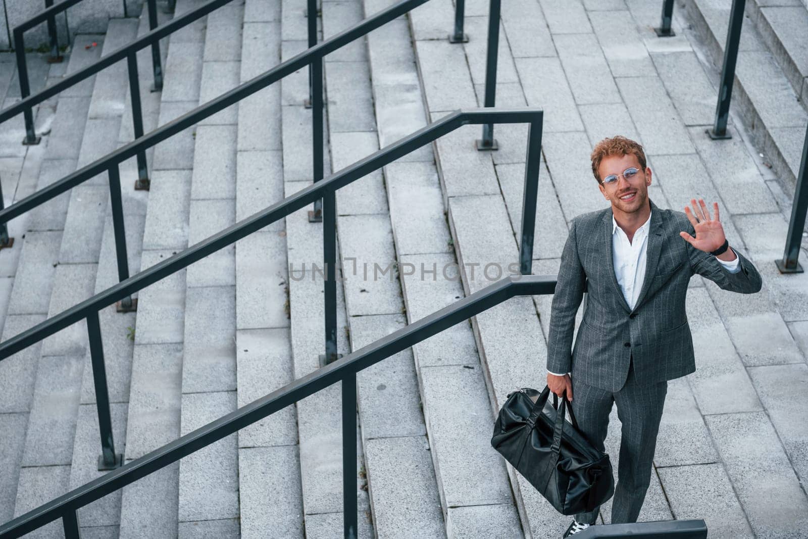Urban beauty. Young businessman in grey formal wear is outdoors in the city by Standret
