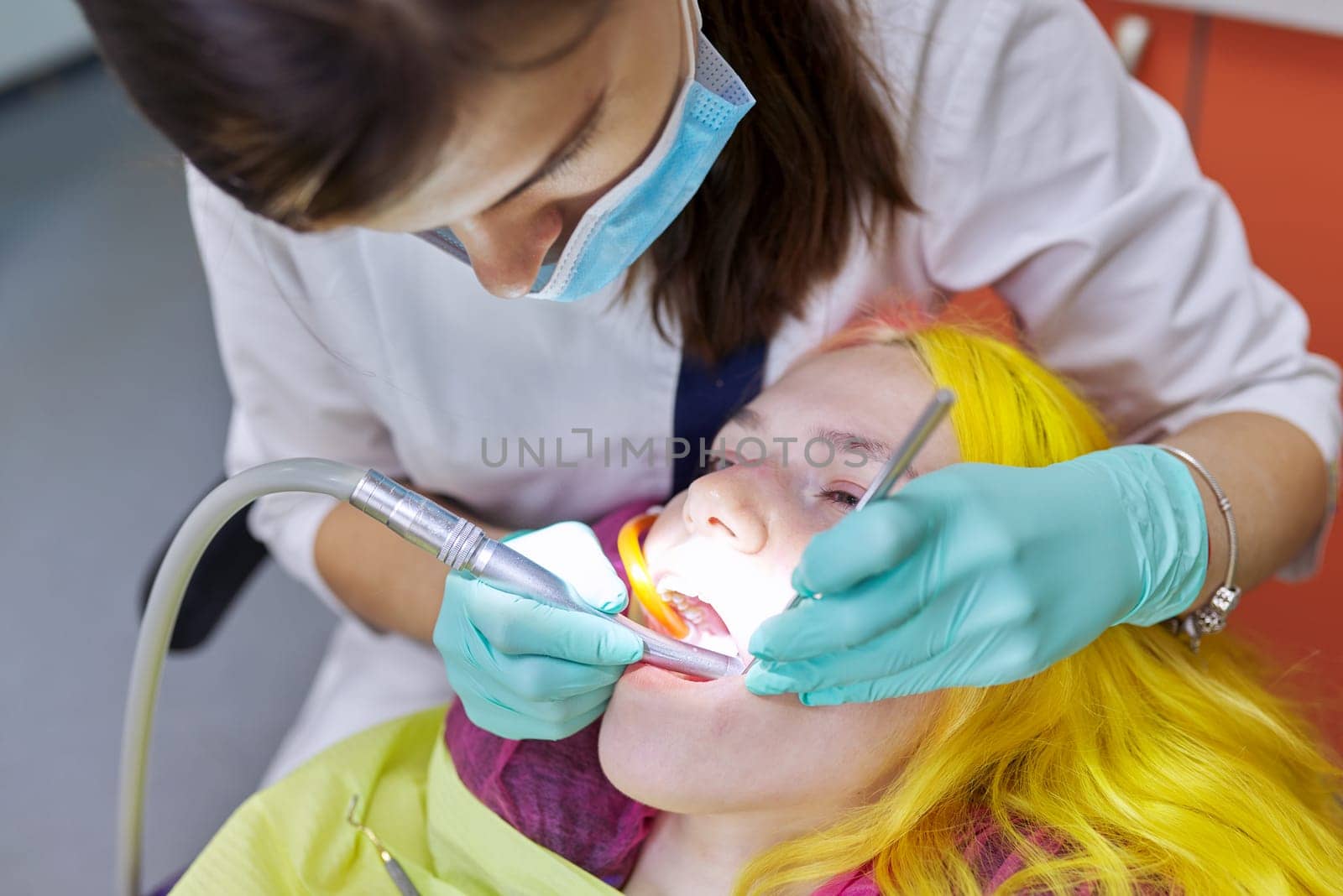 Female dentist treating teeth to patient, young woman in chair at dental clinic by VH-studio