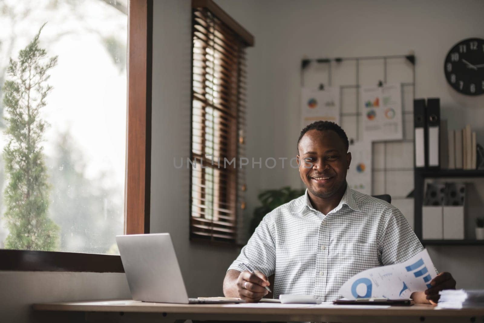 Portrait of handsome African black young business man working on laptop at office desk..
