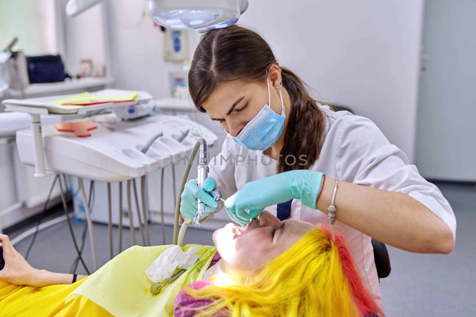 Female dentist treating teeth to patient, young woman in chair at dental clinic by VH-studio