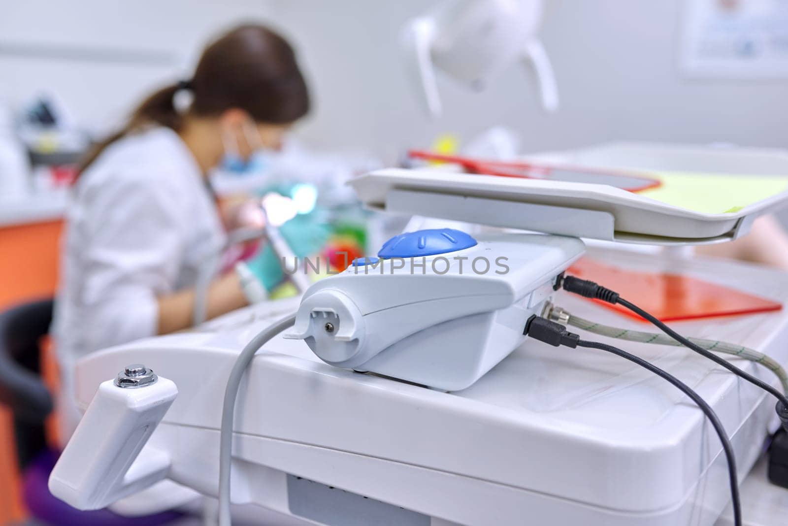 Dental office background, professional equipment, doctor treating teeth to patient out of focus.