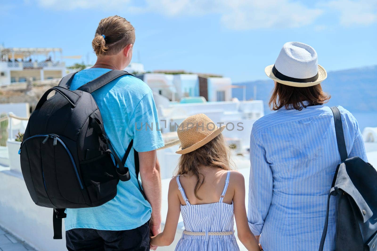Mom dad and daughter happy travelers on the famous picturesque Greek island of Santorini by VH-studio