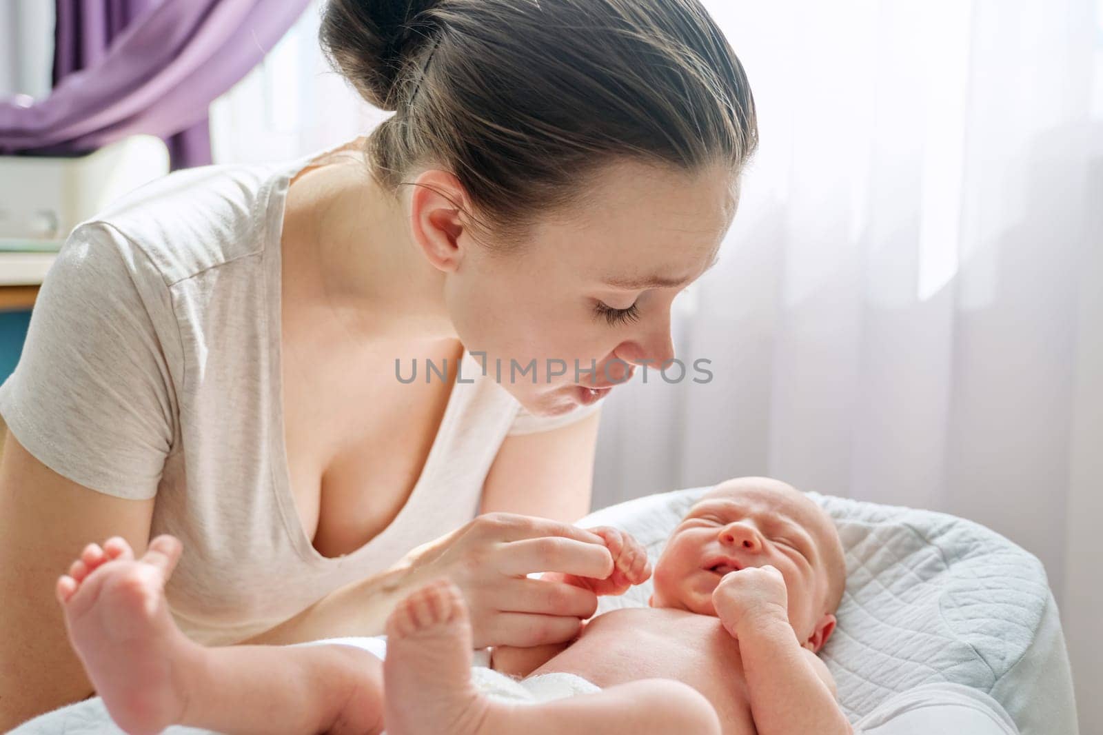 Young mom talking to crying newborn baby son. Infancy, motherhood, parenthood, love, family concept