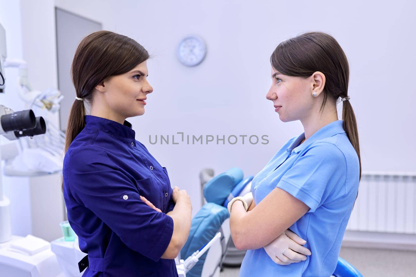 Team of two doctors women dentists in the dental office, female colleagues look at each other, view in profile. Medicine, dentistry and health care concept
