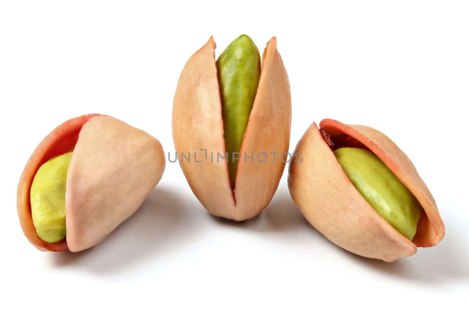 Three turkish red pistachios (Antep Fistigi) peeled green nuts visible under shell, isolated on white background.