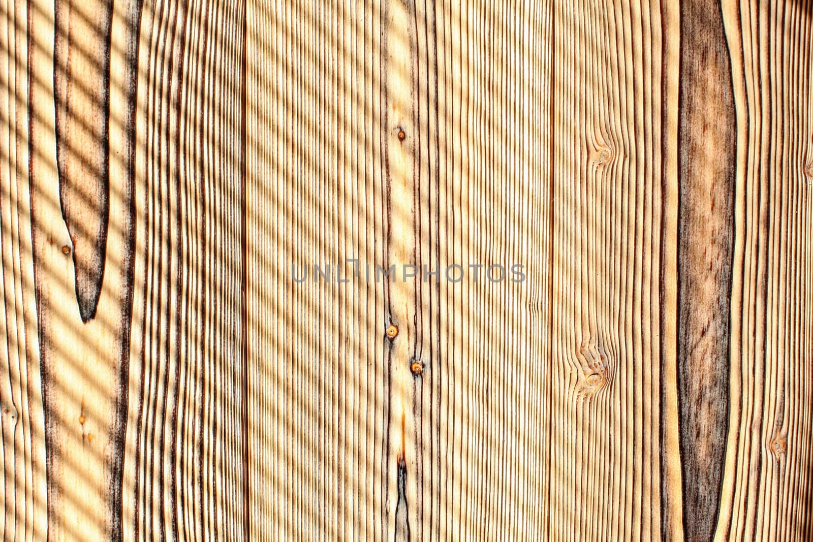 Desk made from wooden boards lit by morning sun, shades leaving diagonal stripes pattern