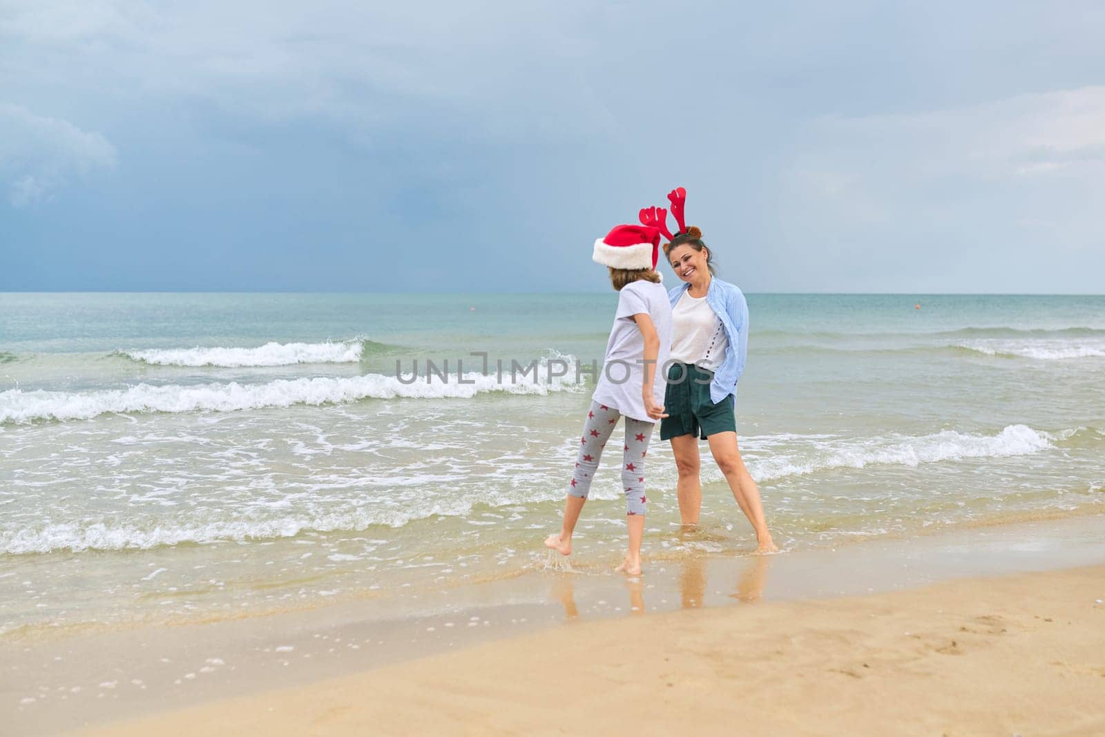 Background sea ocean beach, mom and daughter child having fun celebrating Christmas and New Year at tropical resort, copy space, vacations family travel tourism concept