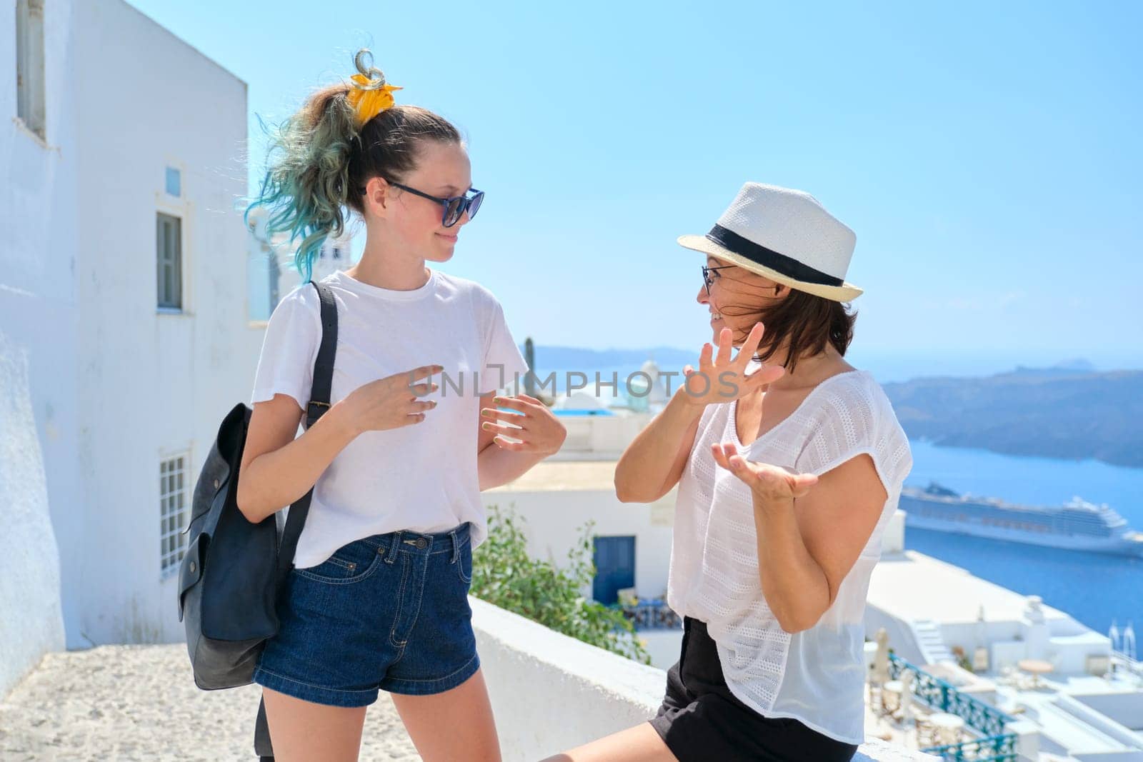 Two happy smiling women, mother and teenage daughter traveling together, luxury travel to the famous greek island of Santorini