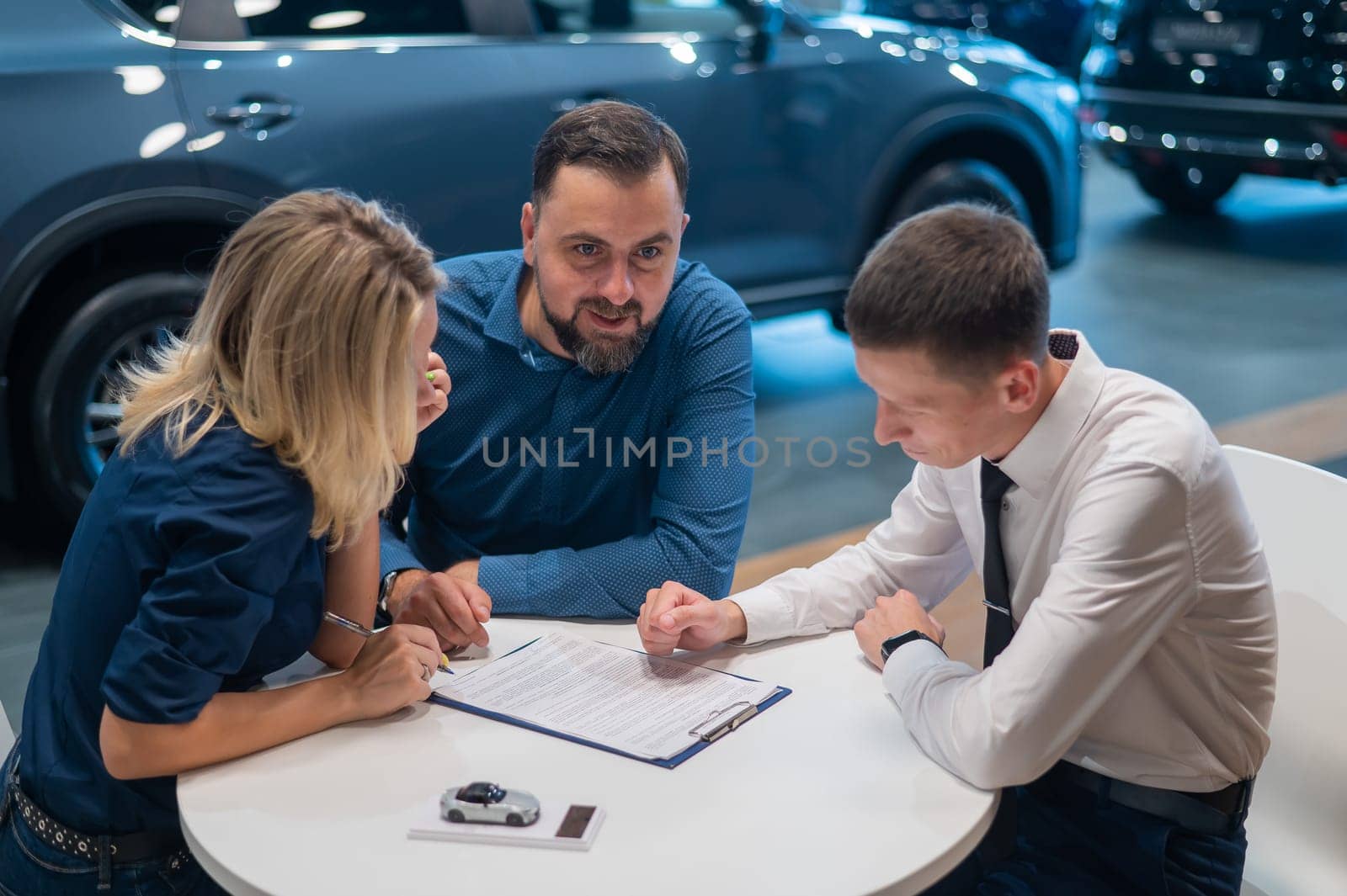 Happy caucasian couple signs a contract for the purchase of a car salon. by mrwed54