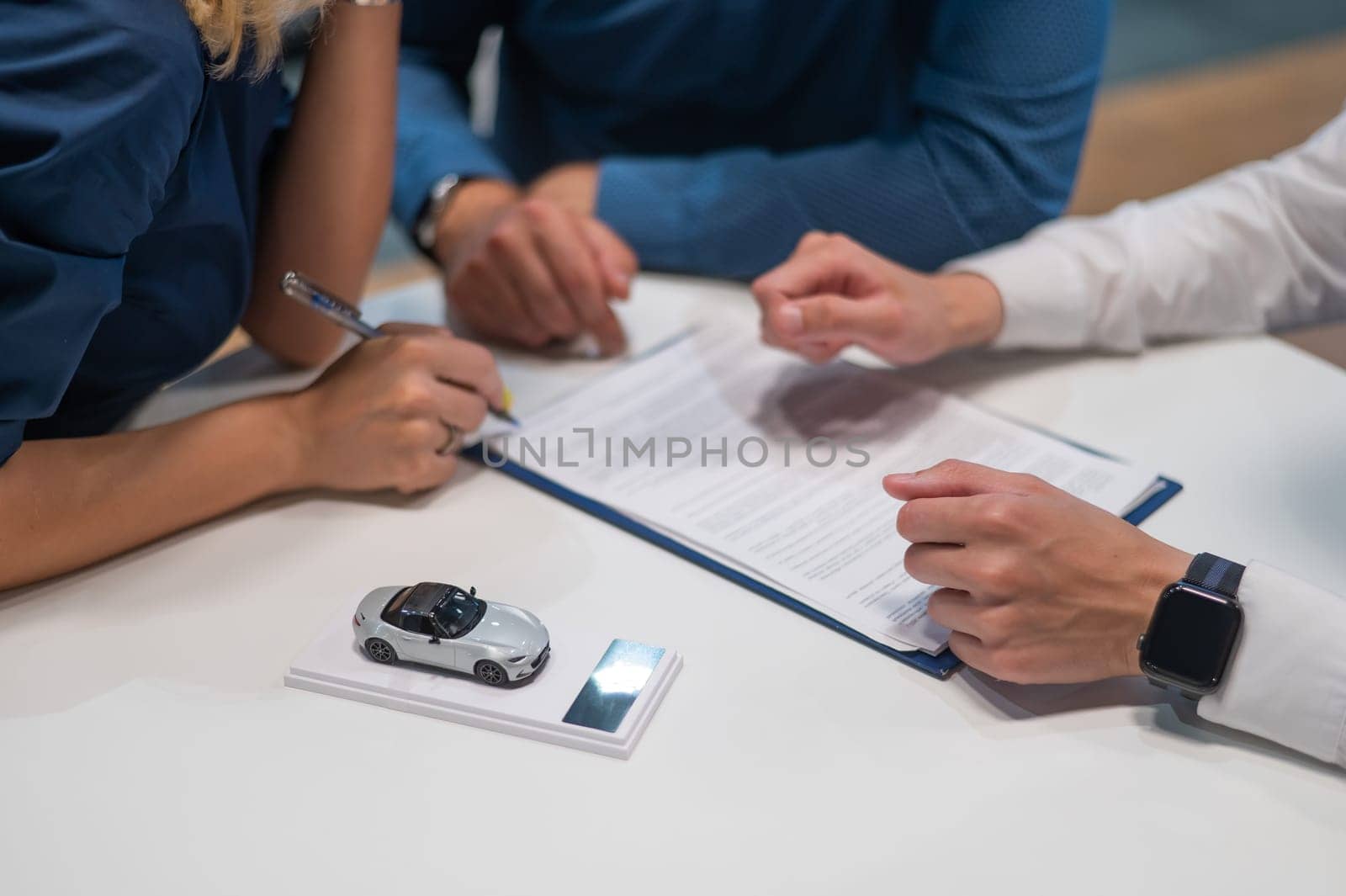 Close-up of the couple's hands signing a contract to buy a car salon