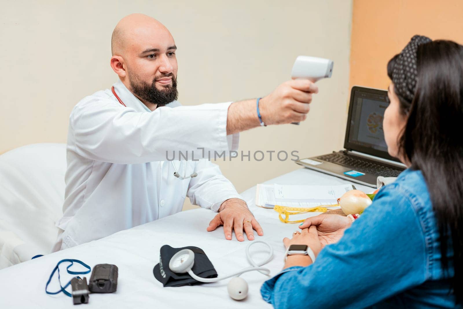 Doctor measuring temperature with infrared gun to female patient, Doctor taking temperature to woman patient in office, Male doctor taking temperature with gun to patient by isaiphoto