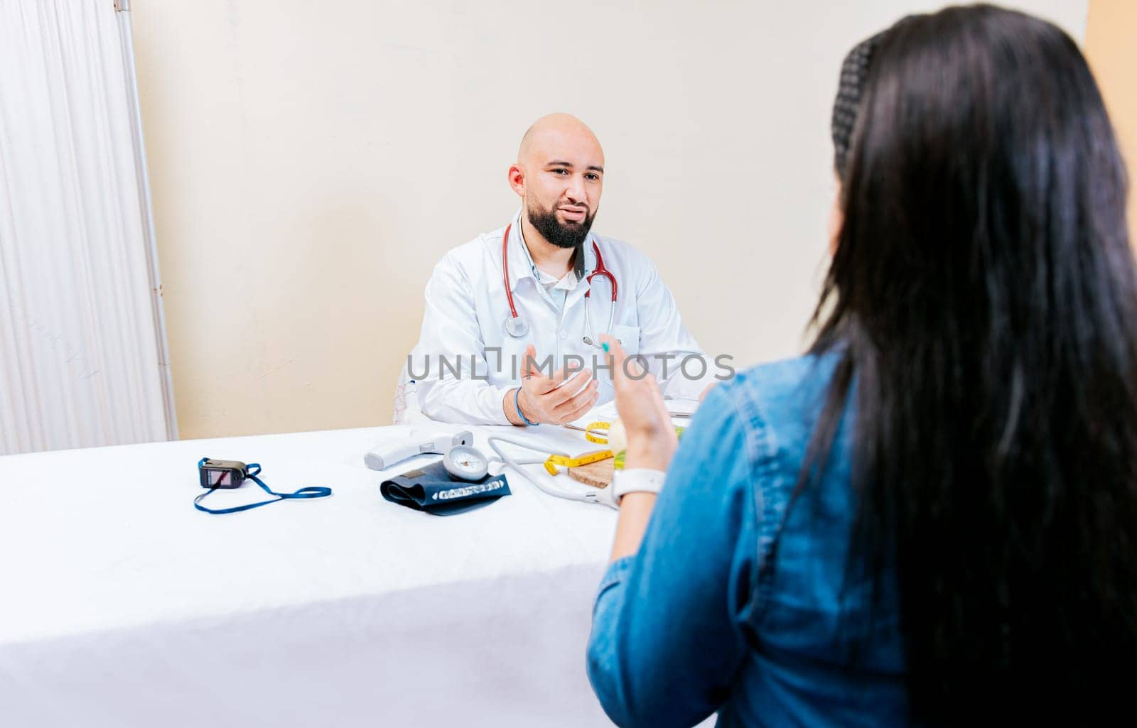 Back view of a female patient talking to the nutritionist. Smiling nutritionist explaining to a female patient, Nutritionist man talking to woman patient in office by isaiphoto