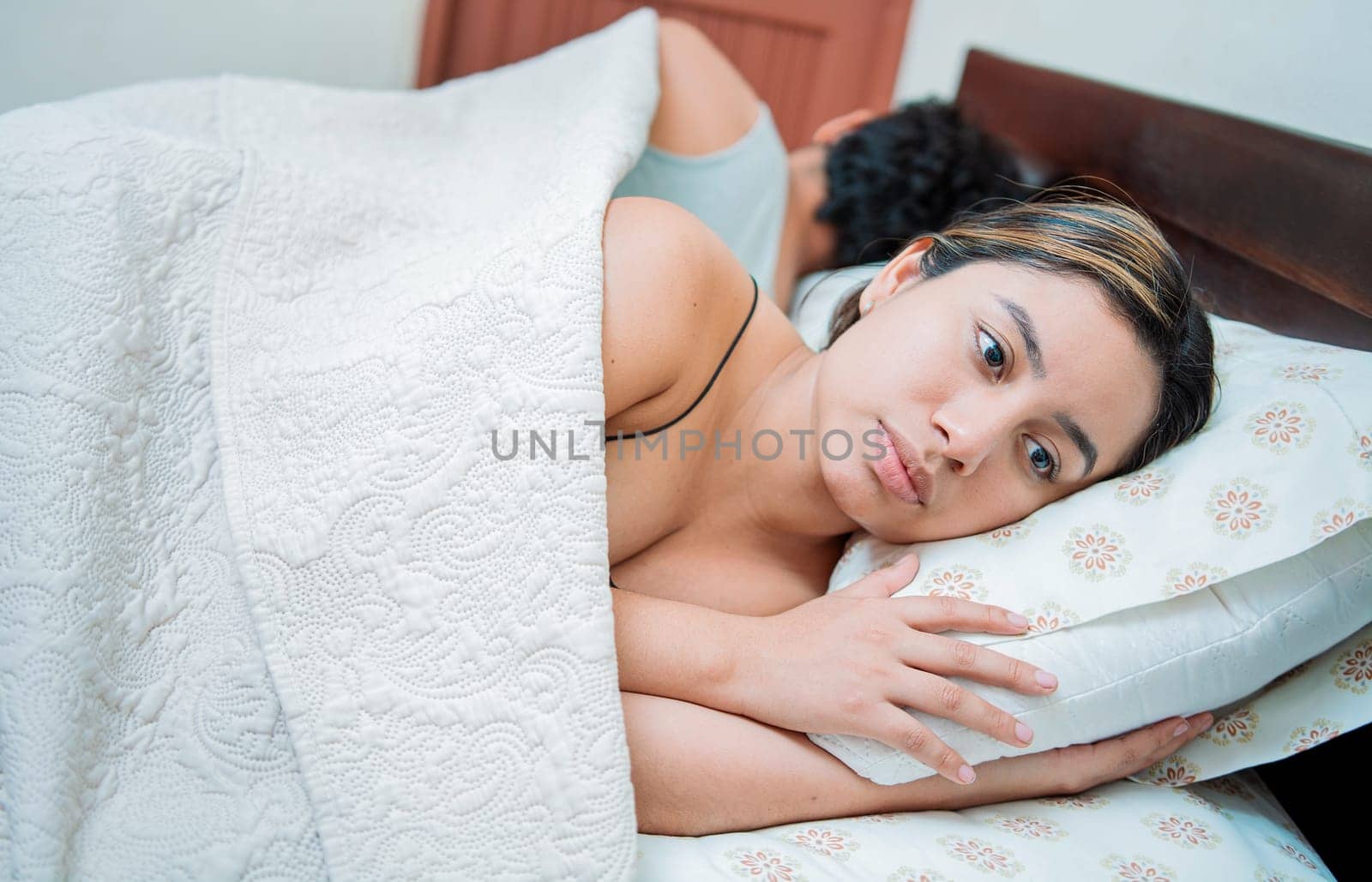 Upset couple sleeping on their backs. Young couple arguing and sleeping apart. Concept of couple problems in bed. Unhappy couple in bed sleeping apart by isaiphoto