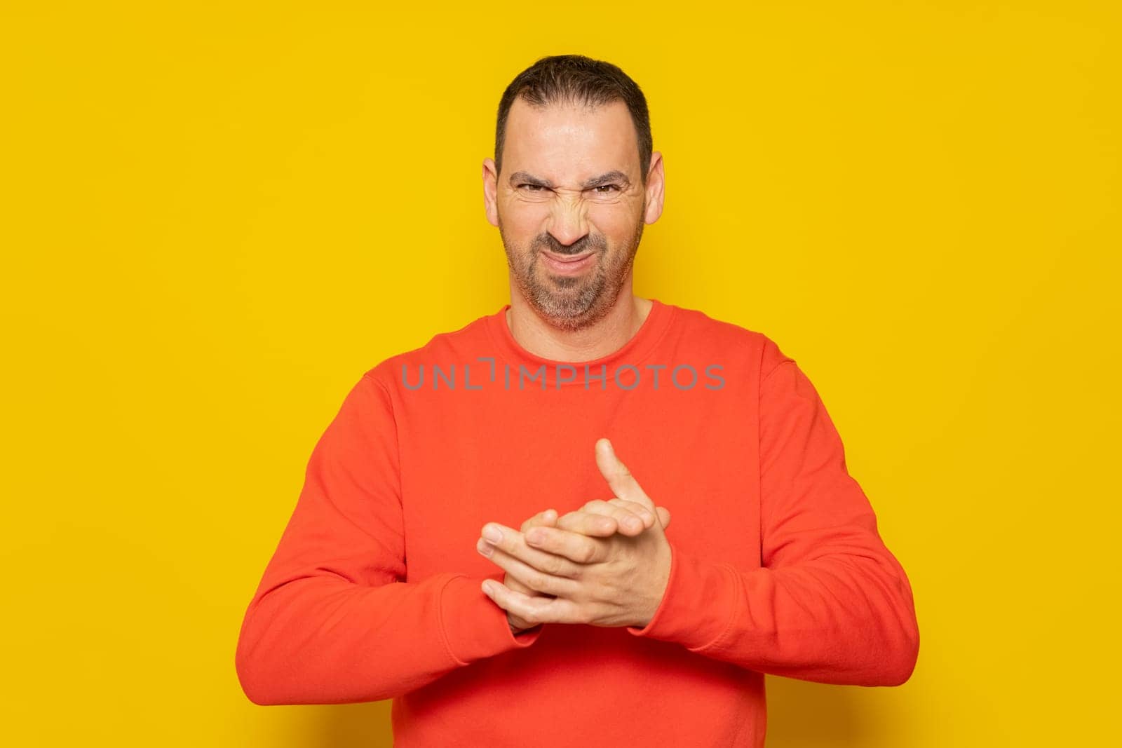 Evil hispanic man rubbing hands on isolated yellow background, person rubbing hands planning some kind of crime