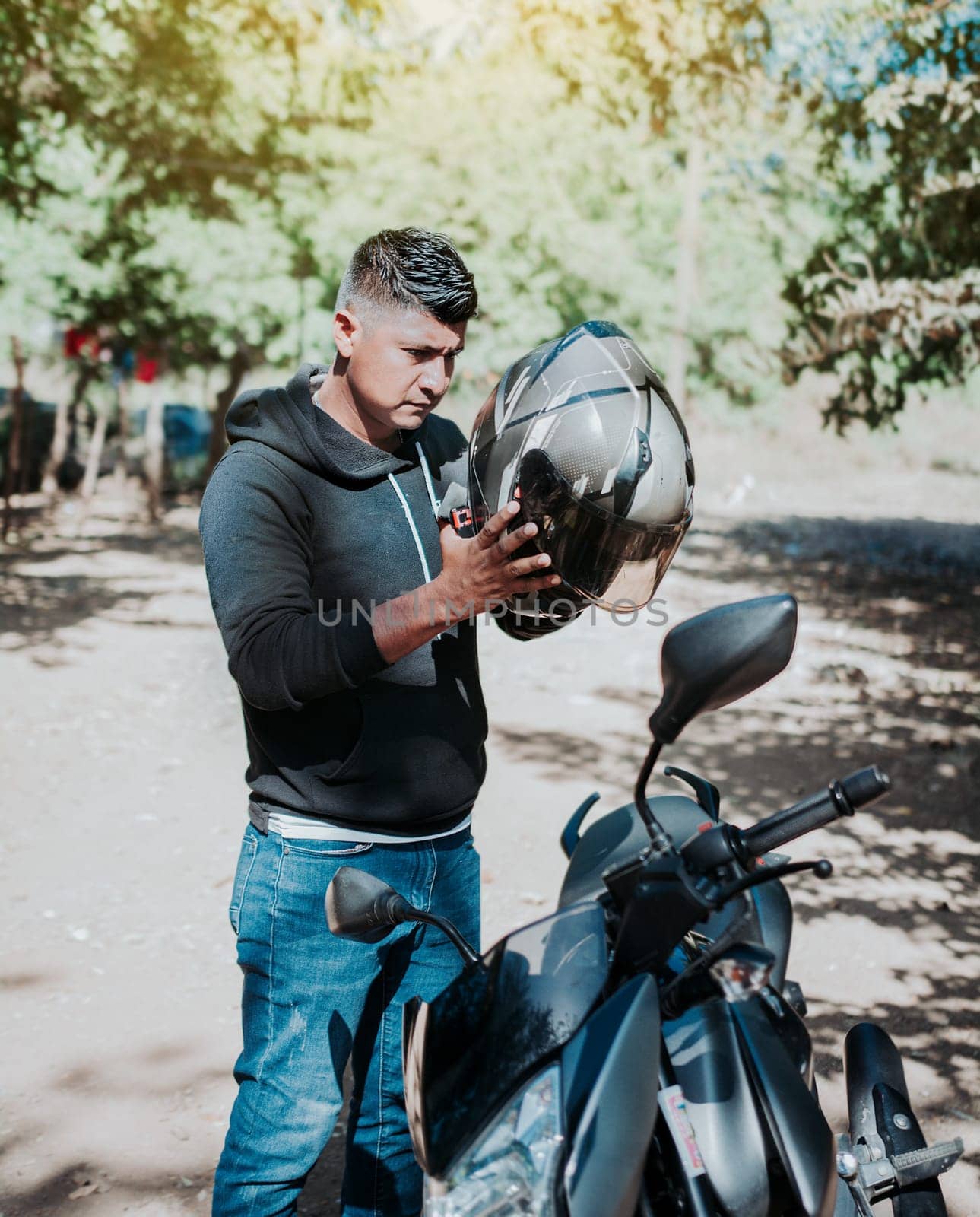 Man on motorcycle putting on helmet. Person on motorcycle putting on safety helmet. Biker motorcycle safety concept. Young motorcyclist man putting on safety helmet by isaiphoto