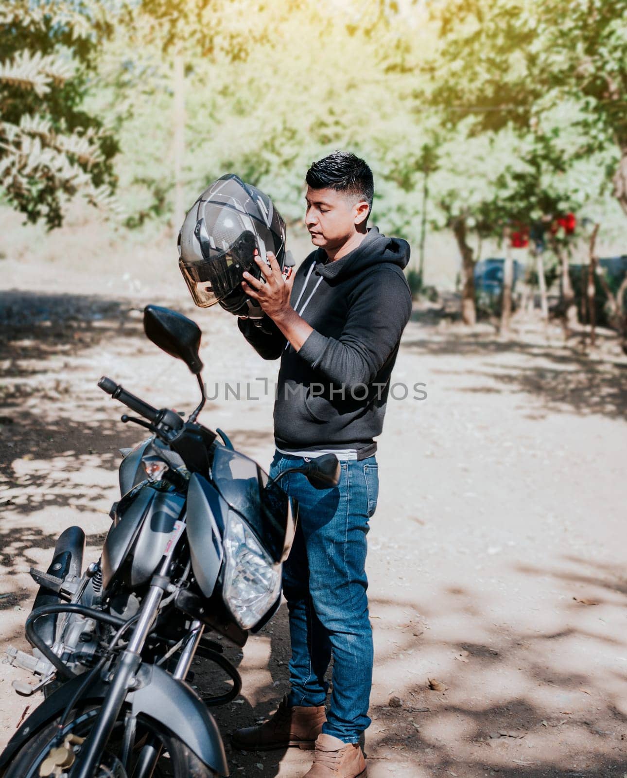 Young motorcyclist man putting on safety helmet, Man on motorcycle putting on helmet. Motorcyclist putting on safety helmet. Biker motorcycle safety concept