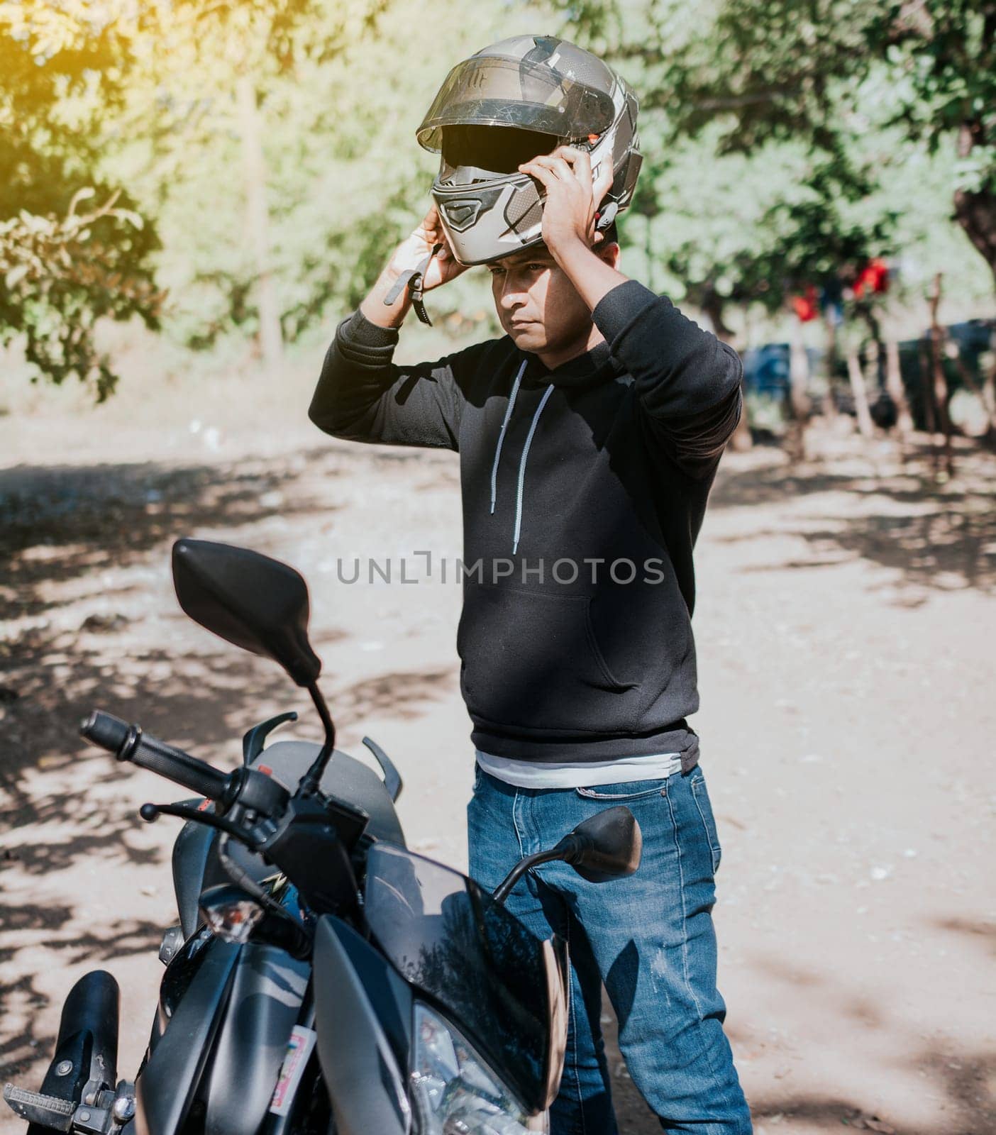 Close-up of motorcyclist man putting on safety helmet. Person on motorcycle putting on safety helmet, Man on motorcycle putting on helmet. Biker motorcycle safety concept by isaiphoto