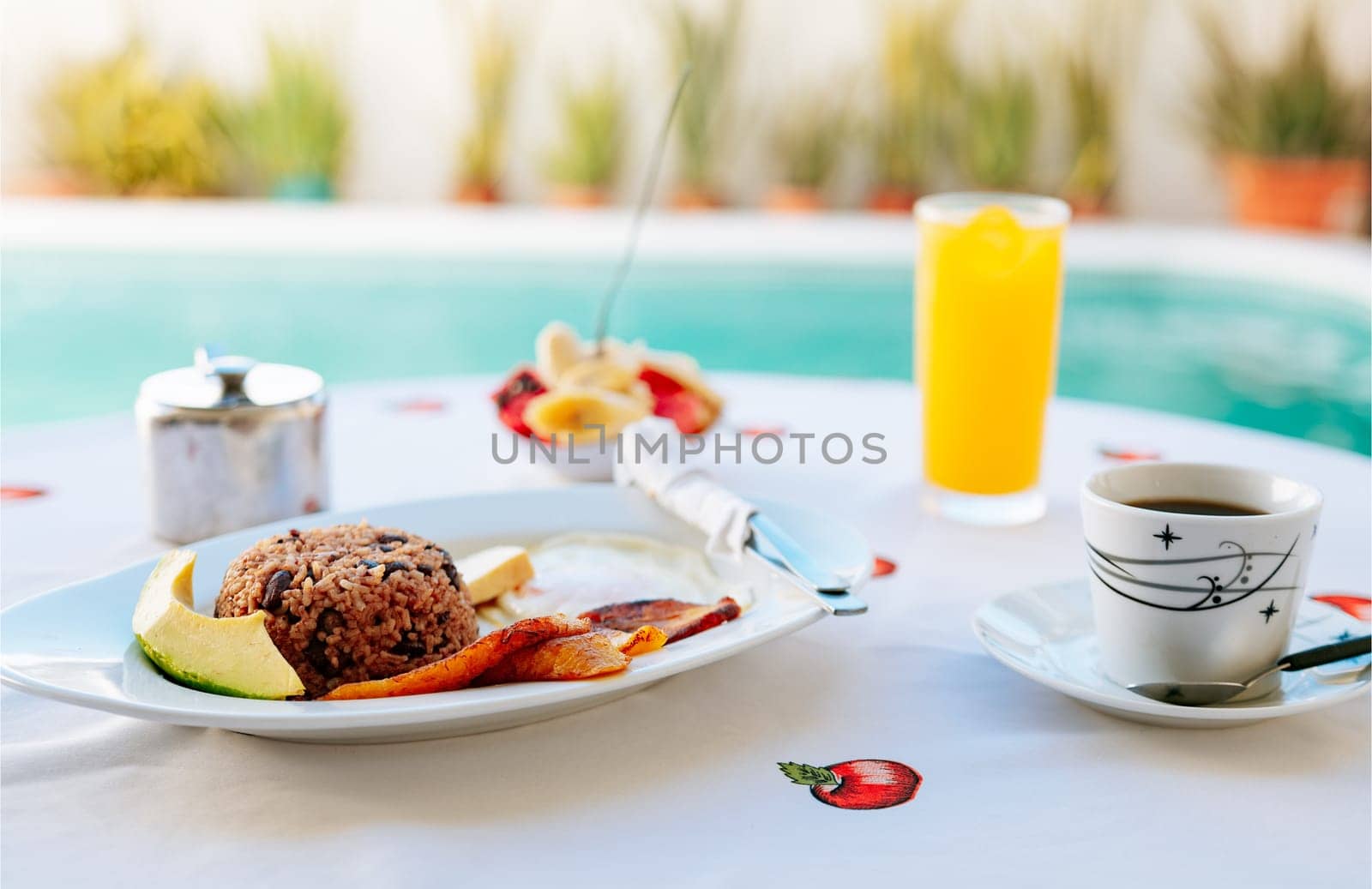 Morning breakfast on the table near a swimming pool. Close-up of a traditional breakfast on a table with a swimming pool in the background. 