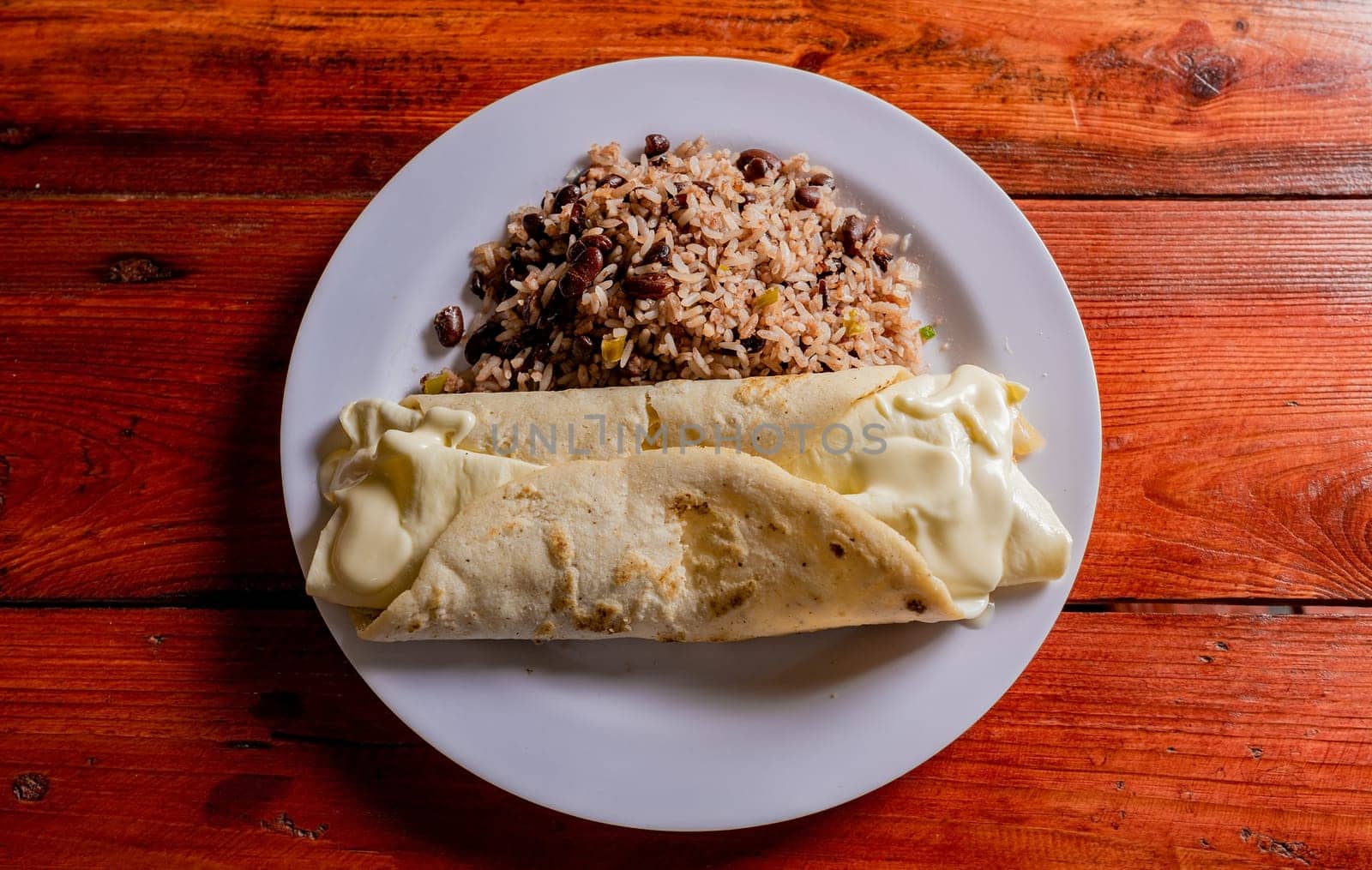 Top view of traditional gallo pinto with Quesillo served on wooden table.  Plate of nicaraguan gallopinto with quesillo on the table. typical nicaraguan foods