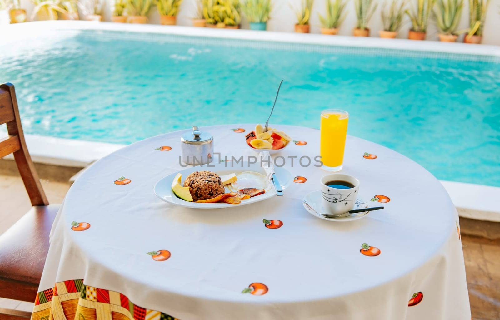 Traditional breakfast served at the table near a swimming pool. Breakfast served on the table with a swimming pool in the background. fruit salad