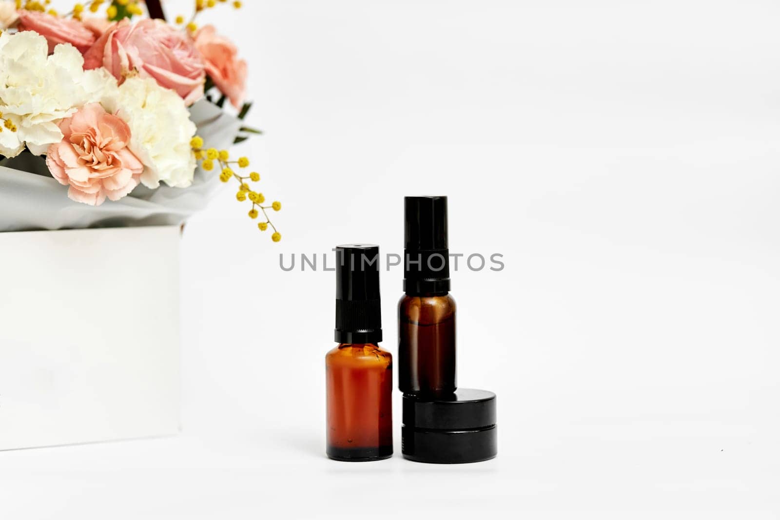 Small glass cosmetic bottle with natural ingredient and spring flower. natural concept
