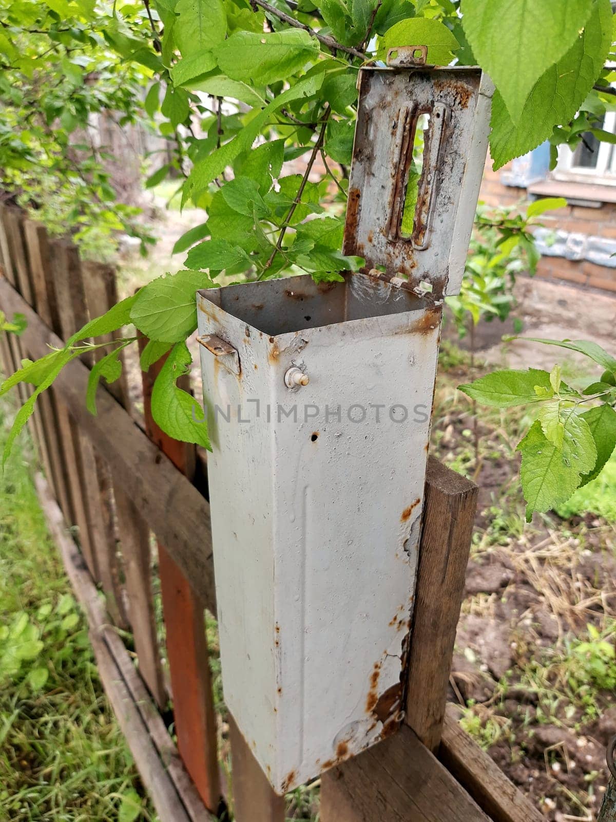 Old gray empty mailbox on a wooden fence close up.