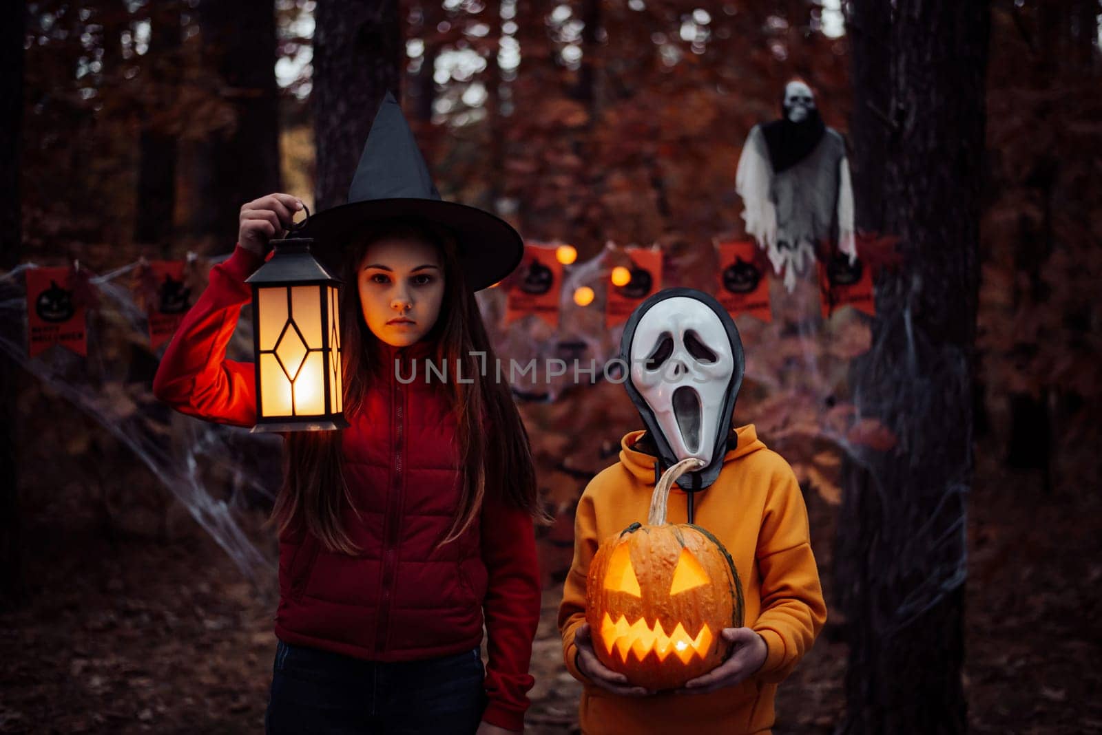 Children in halloween costumes with jack-o-lantern in dark spooky forest by VitaliiPetrushenko