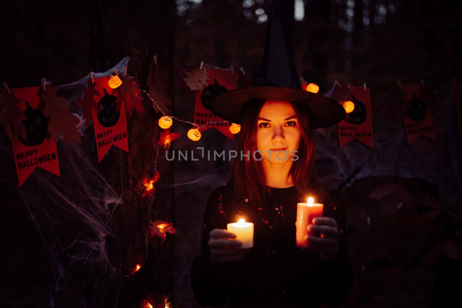 Portrait of a girl with bright candles in forest at night