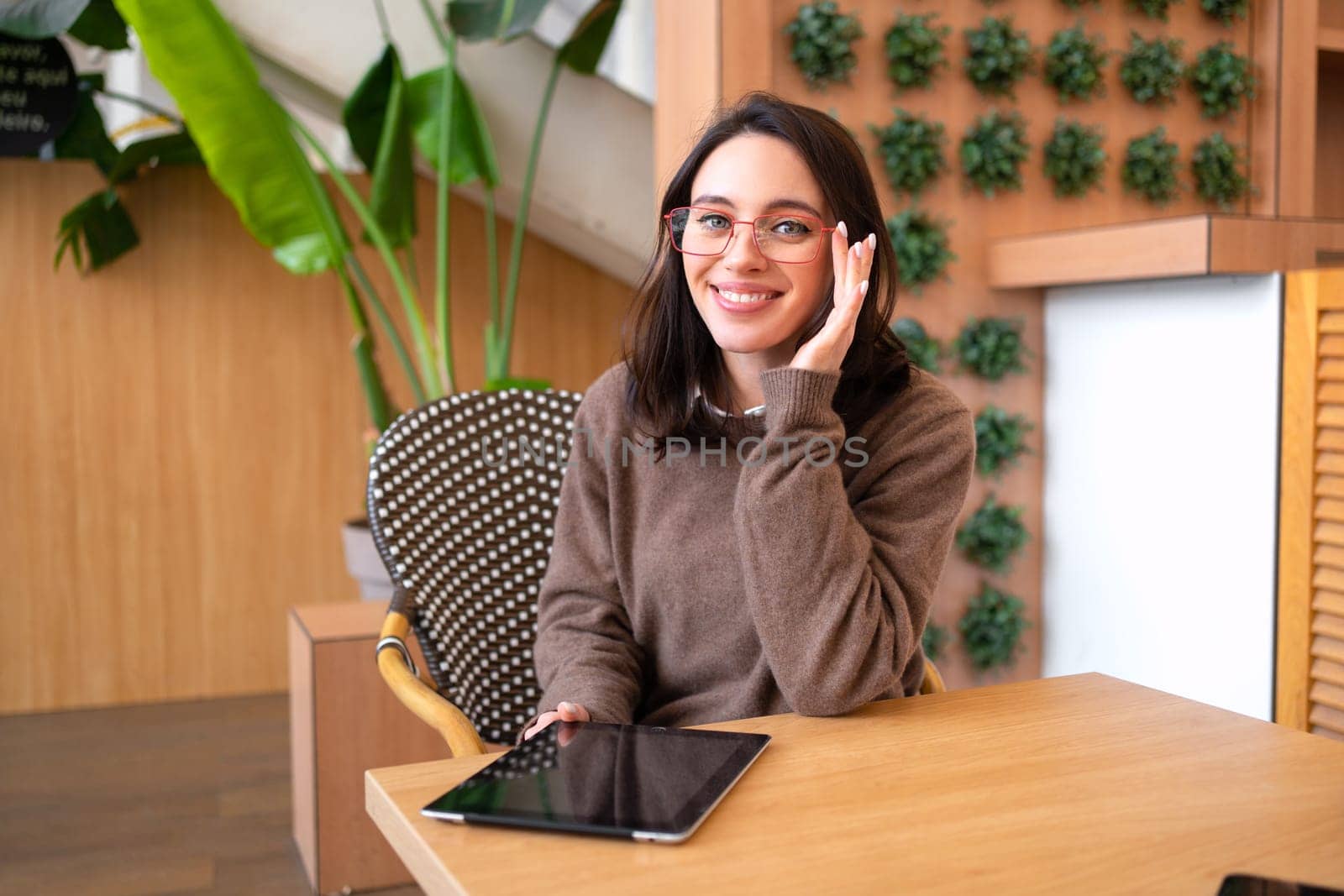 Modern technologies and communication. Portrait of happy woman with tablet computer sitting at her desk. Young female person studying or working online on touch pad