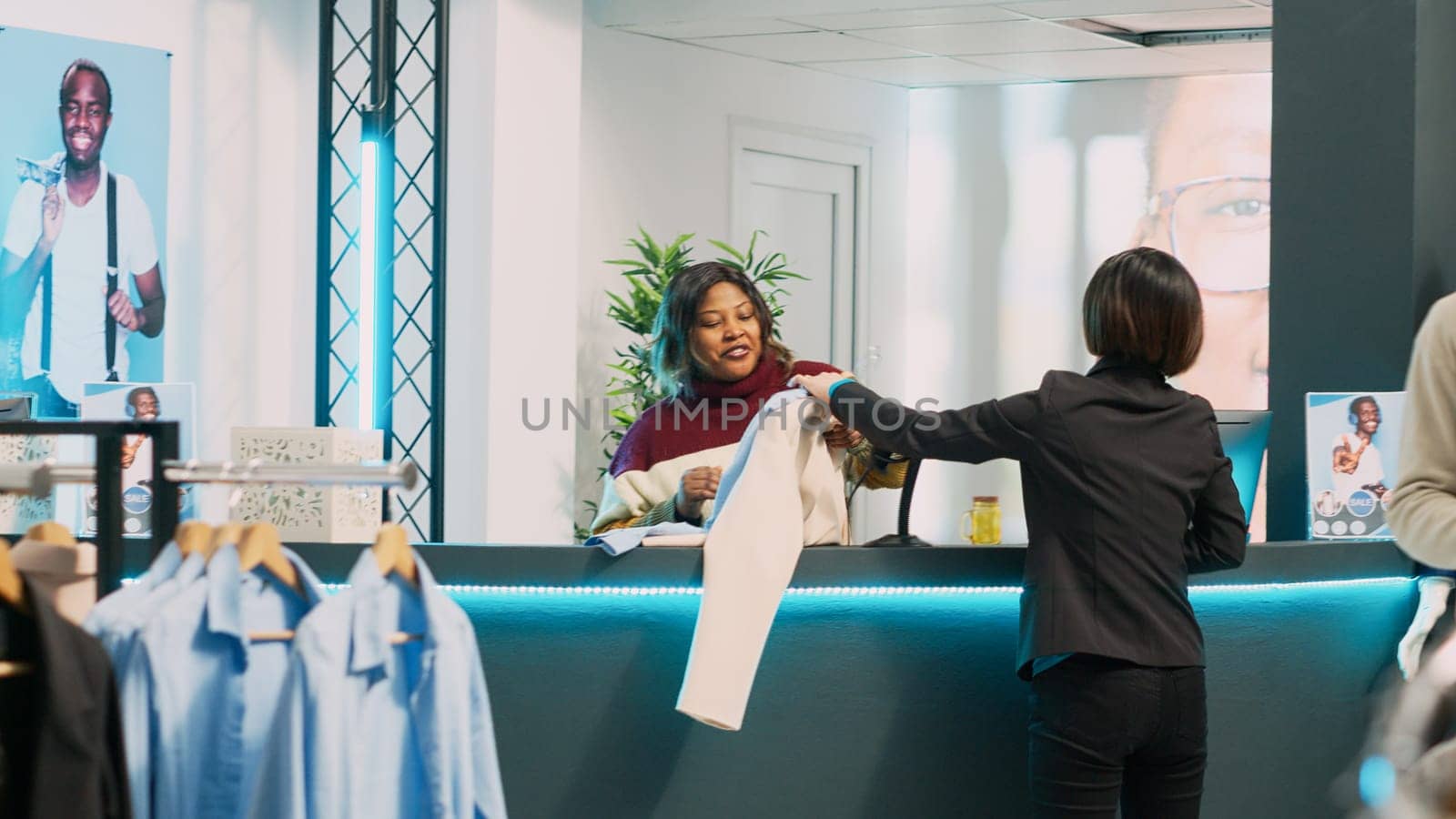 Female shopper buying clothes collection in retail store by DCStudio