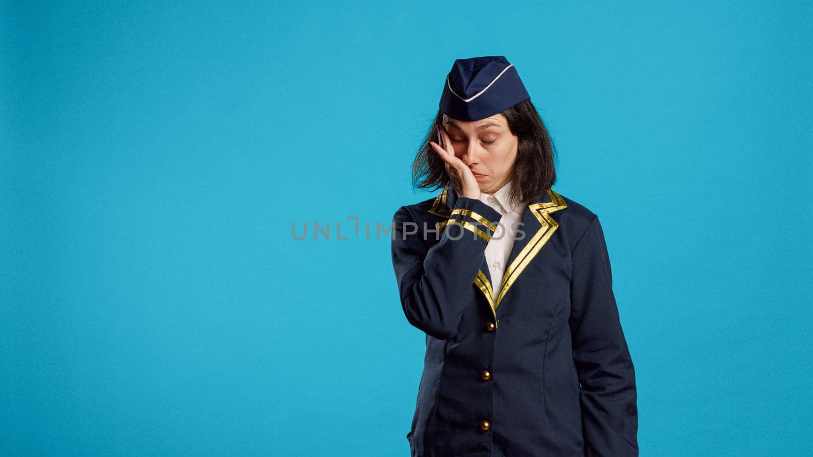 Air hostess feeling tired and yawning in studio, being drained and worn out after commercial flight work. Aircrew member dressed as stewardess being exhausted and falling asleep.