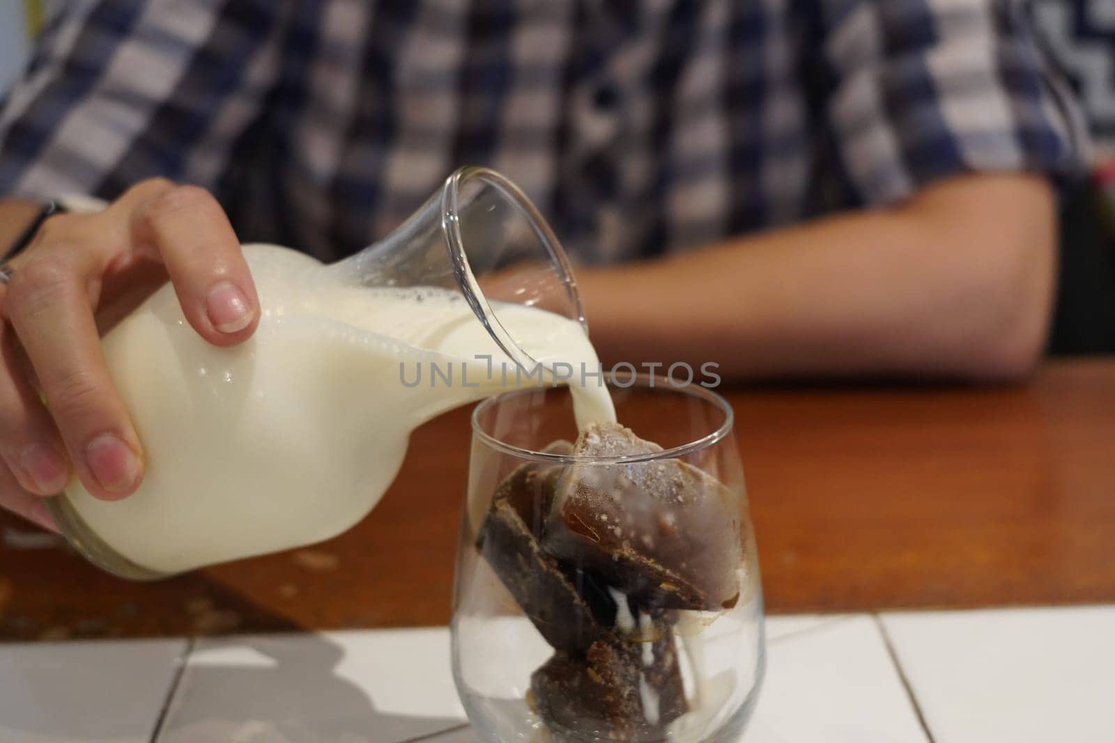 Milk Being Poured Into Glass Iced Coffee on the table in a cafe.