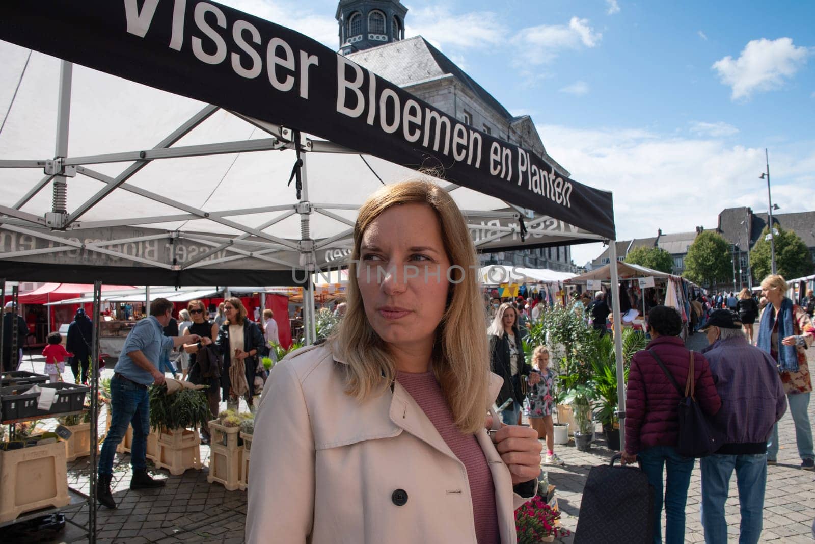 People walk among Variety of flower choices at the market in the central square in Maastricht, Netherlands, August 27, 2021. High quality photo