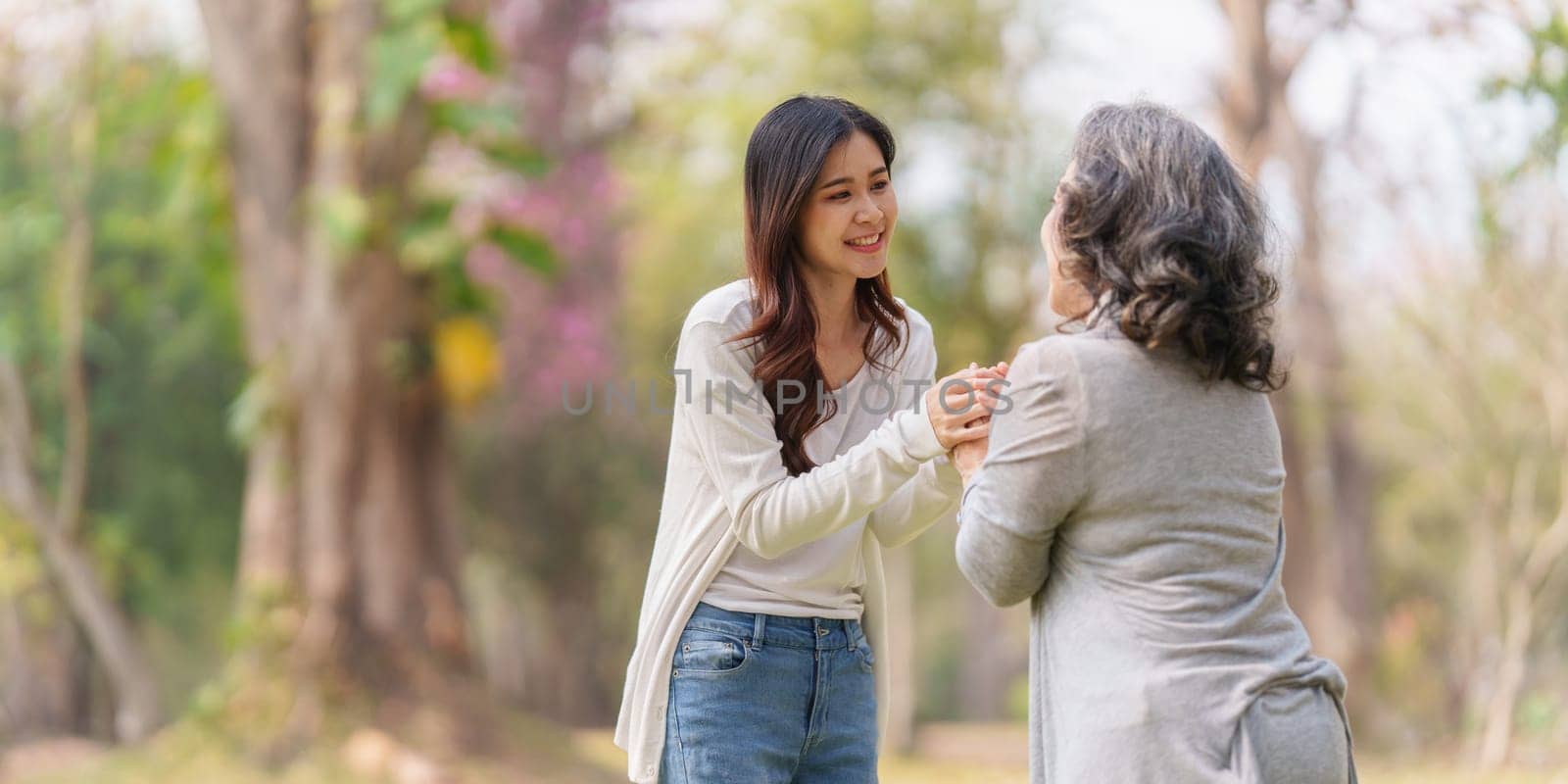 Close up of Adult daughter holding her elderly mother hand with love and walk together by itchaznong