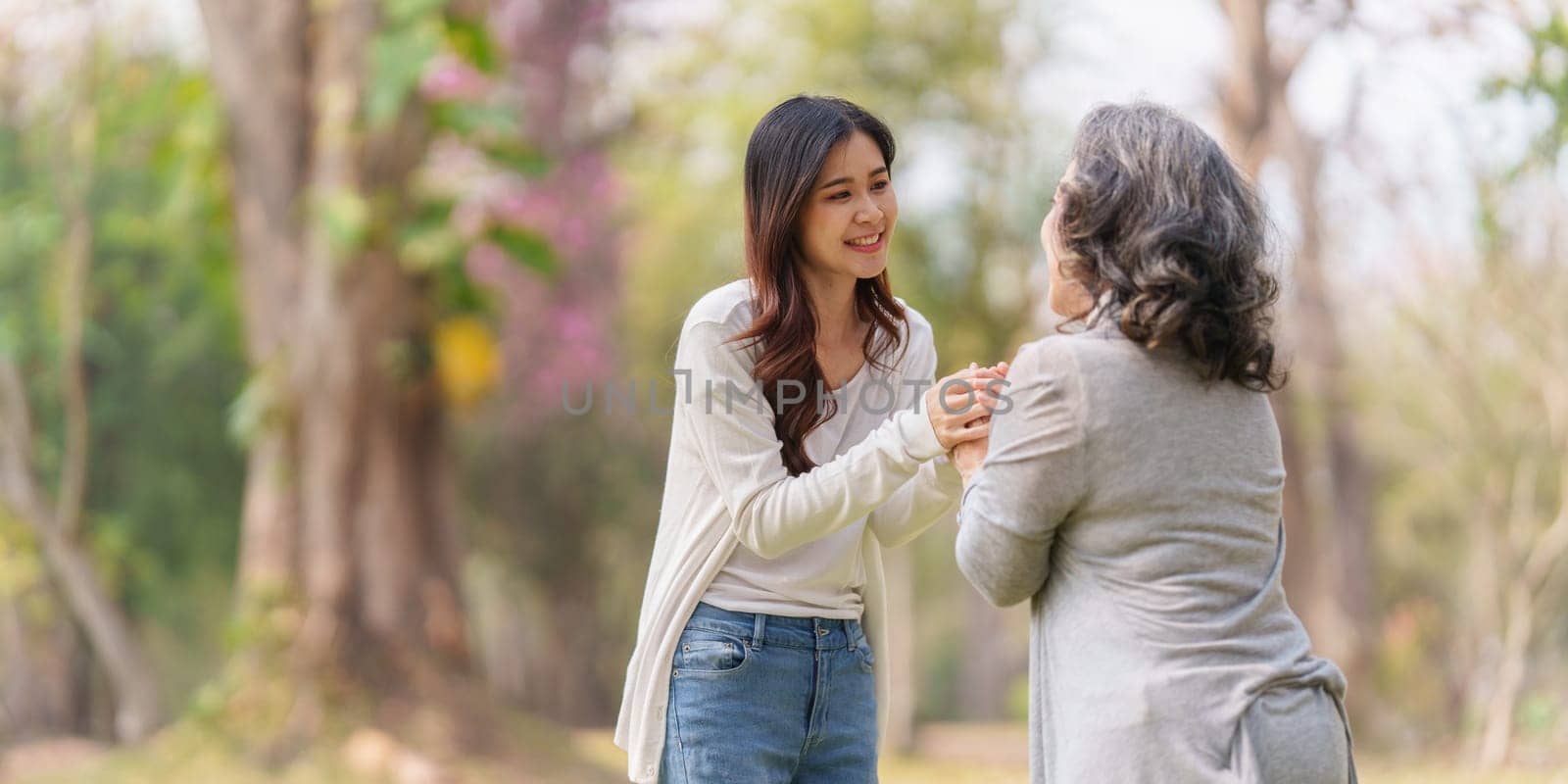 Close up of Adult daughter holding her elderly mother hand with love and walk together.