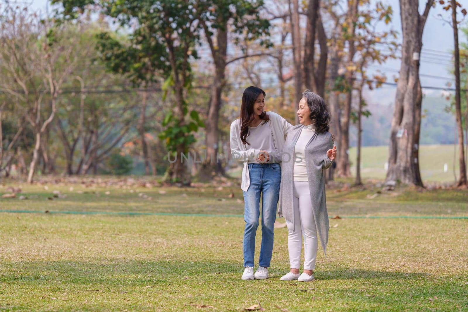 Adult daughter holding her elderly mother hand with love and walk together.