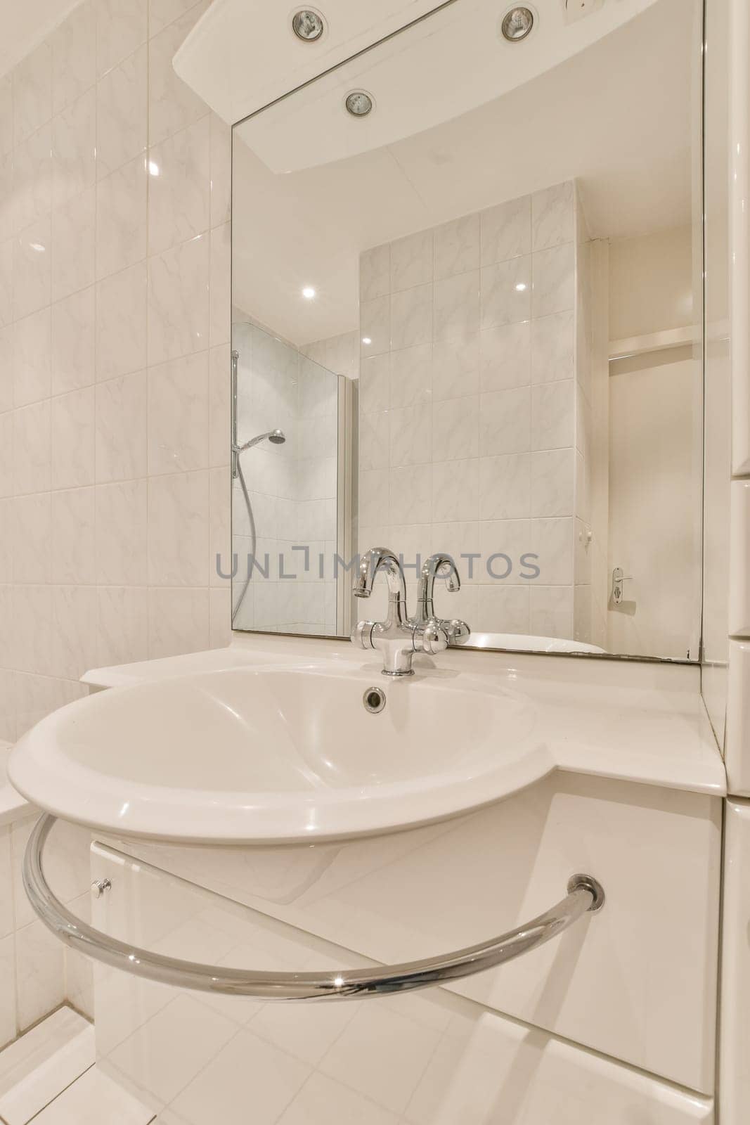 a modern bathroom with white tile walls and flooring, including a large mirror over the bathtub on the wall