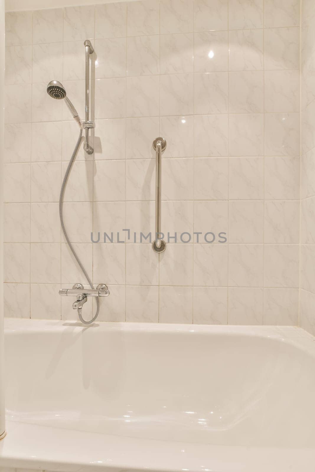 a white bathtub in the corner of a bathroom with a shower head and hand rail attached to the wall