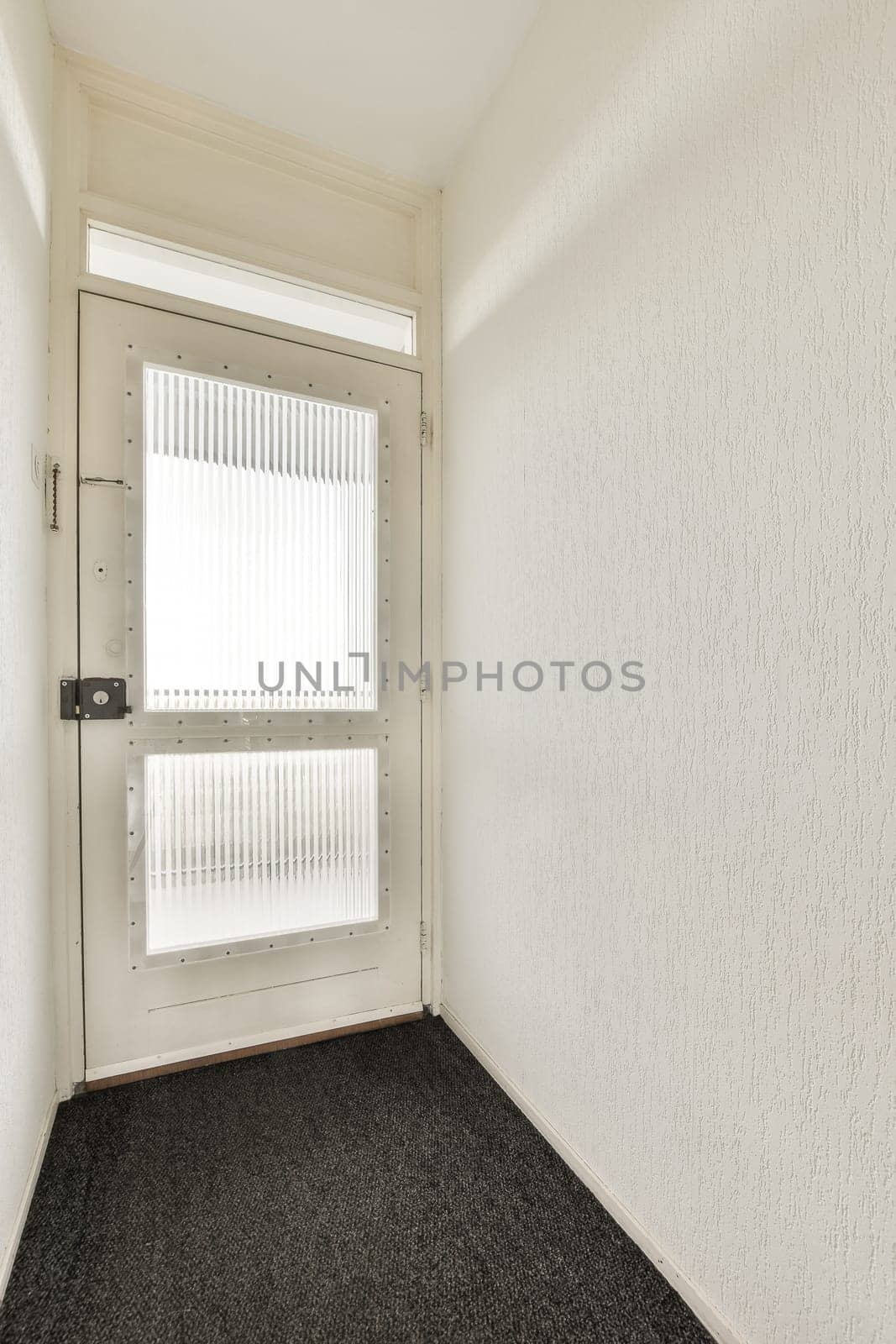an empty room with white walls and black carpet on the floor, there is a small window in the corner