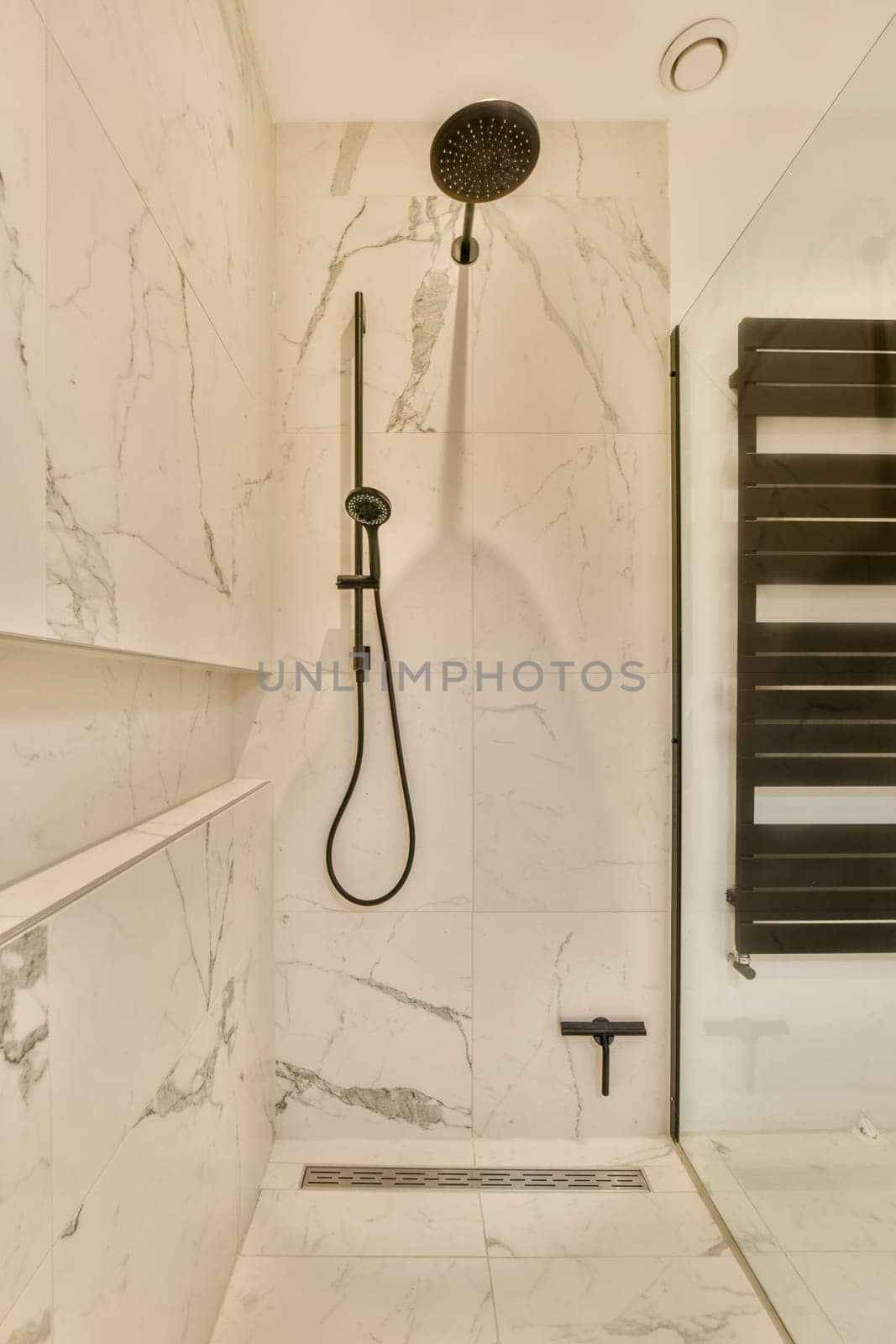 a marble bathroom with a shower and a shower head by casamedia