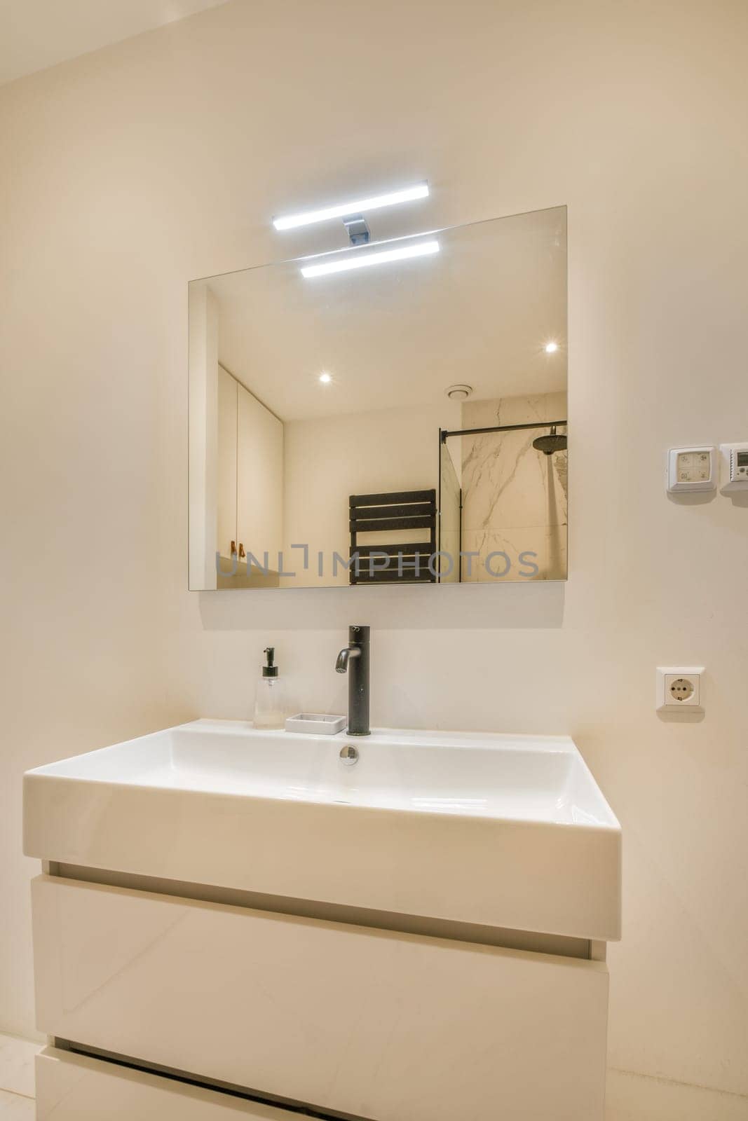 a white bathroom with a sink and a mirror by casamedia