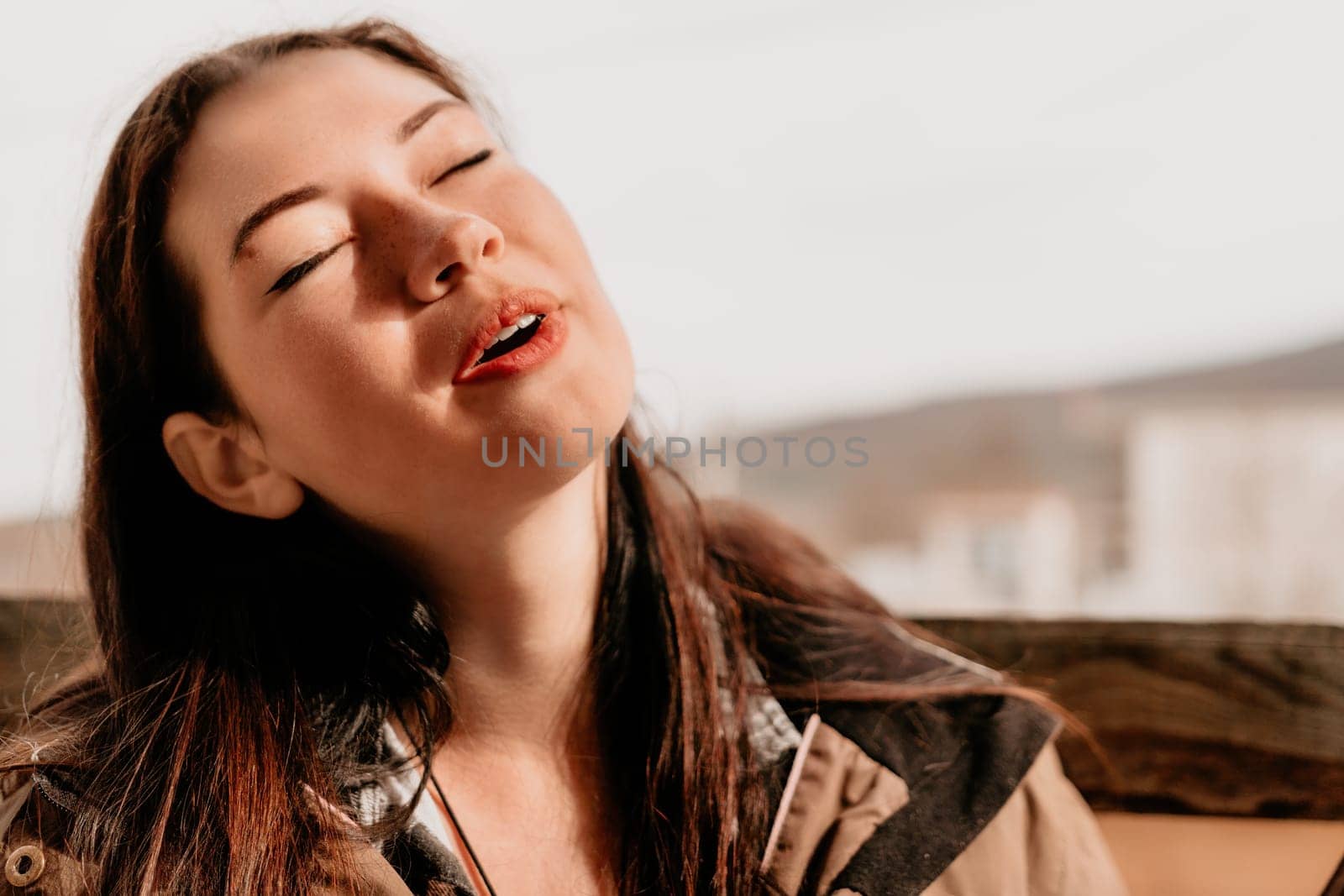 Happy young smiling woman with freckles outdoors portrait. Soft sunny colors. Outdoor close-up portrait of a young brunette woman and looking to the camera, posing against autumn nature background by panophotograph