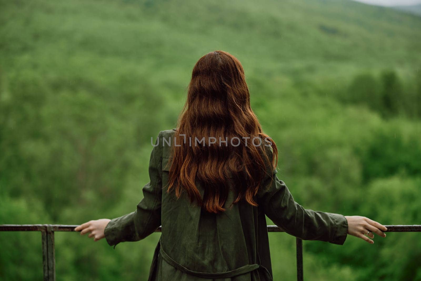 a red-haired woman with beautiful, well-groomed, long hair stands with her back to the camera and enjoys the view of the forest by Vichizh