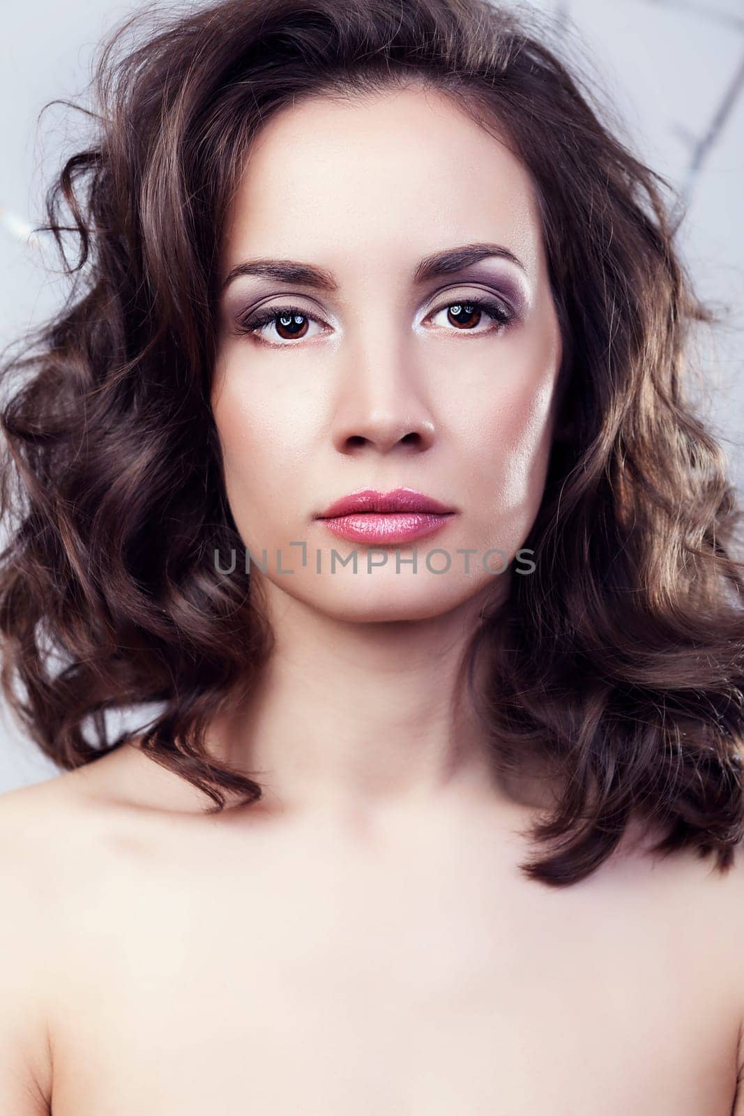 Portrait of gorgeous woman on grey background in studio photo. Professional make up and hairstyle. Elegance and romance