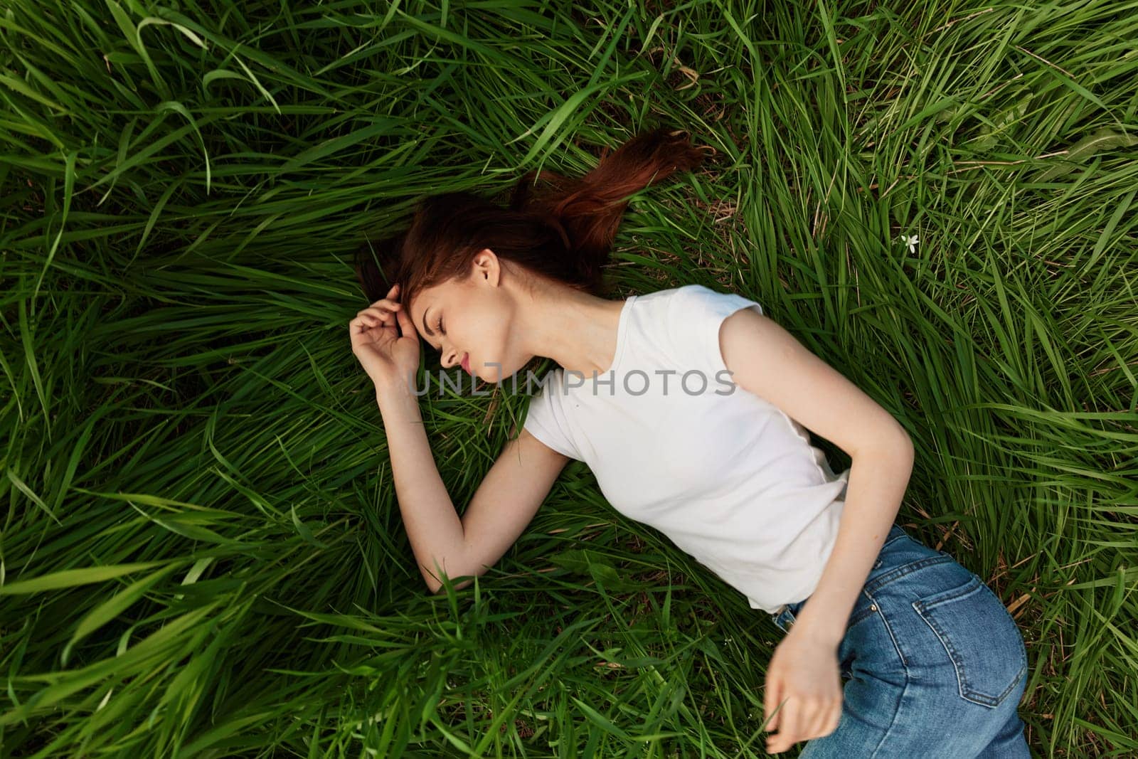 woman lies in tall grass falling asleep in nature. High quality photo